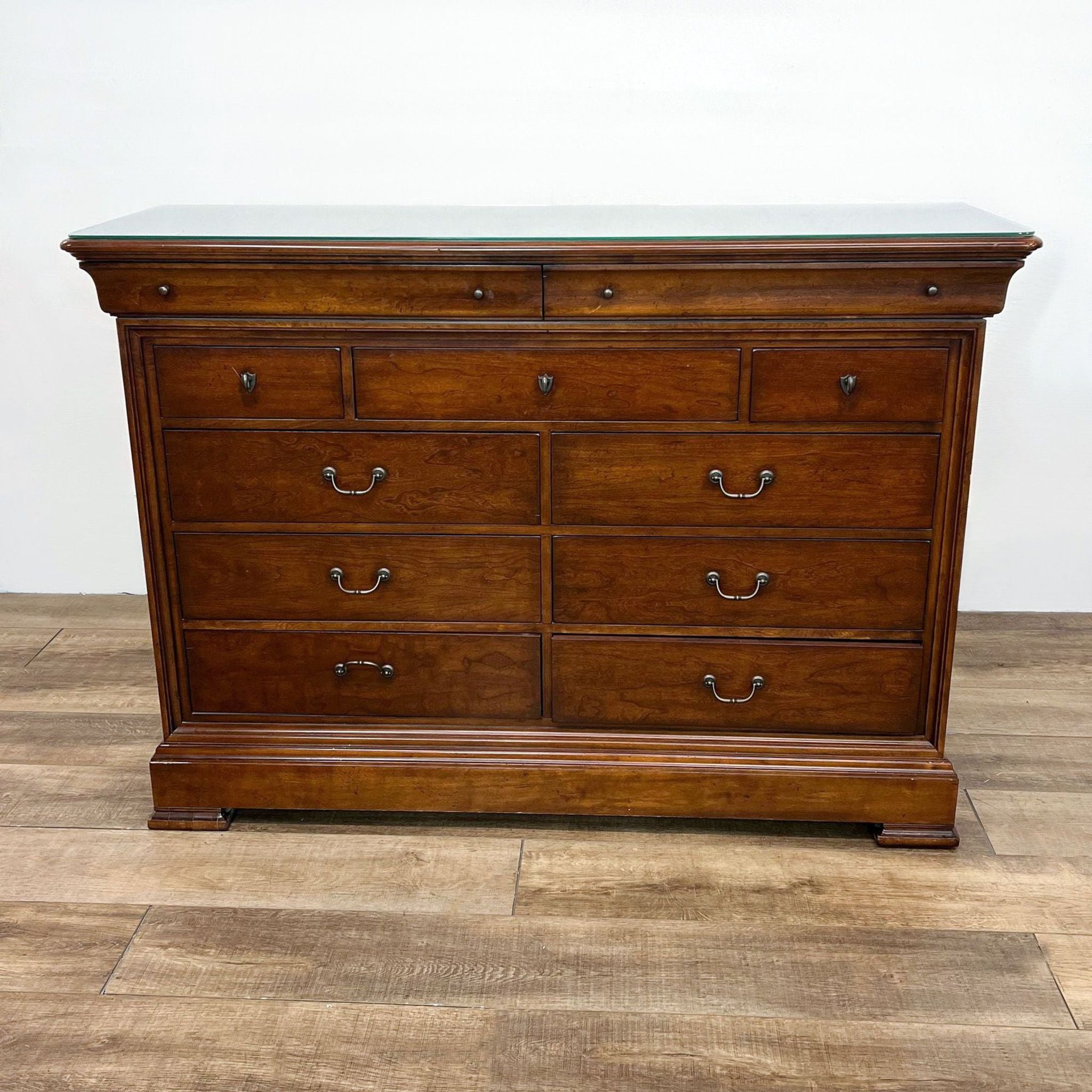 Elegant Thomasville wooden dresser with a glass top, 11 drawers, and polished brass handles.