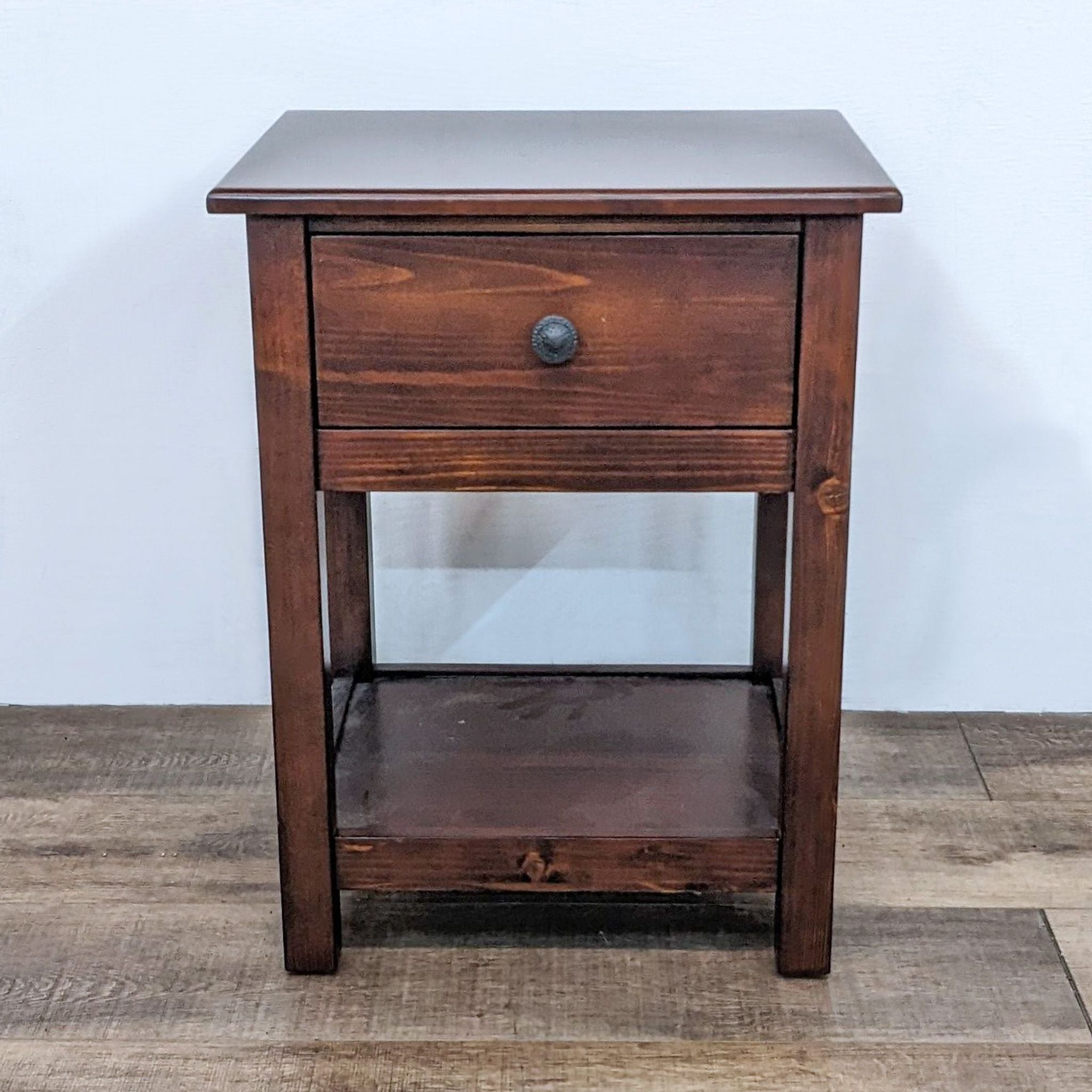 Pottery Barn Kids wooden end table with a drawer and lower shelf, set on a wooden floor against a white wall.