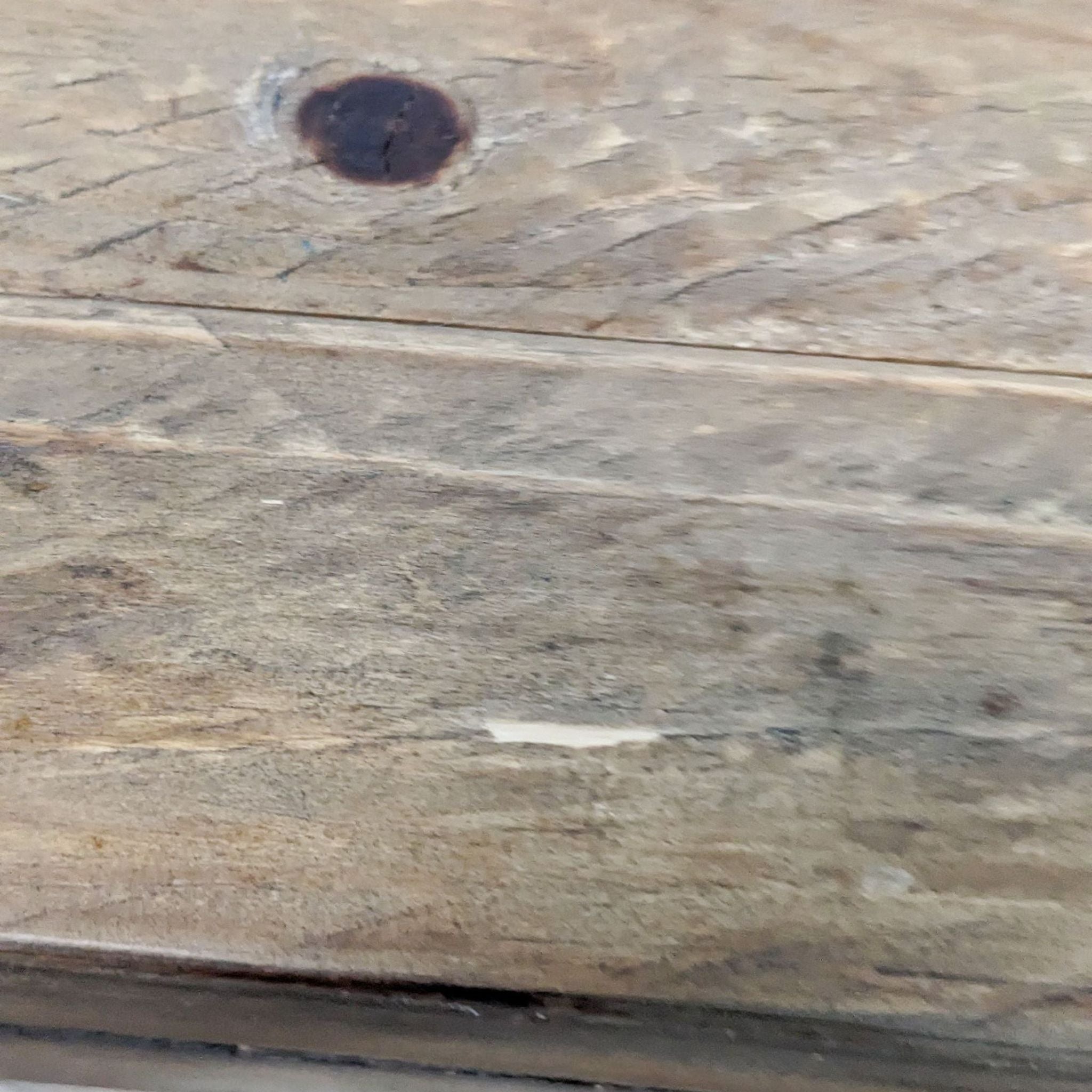 Close-up of a Scandinavian Designs wooden table surface showing textured wood grain and a knot.