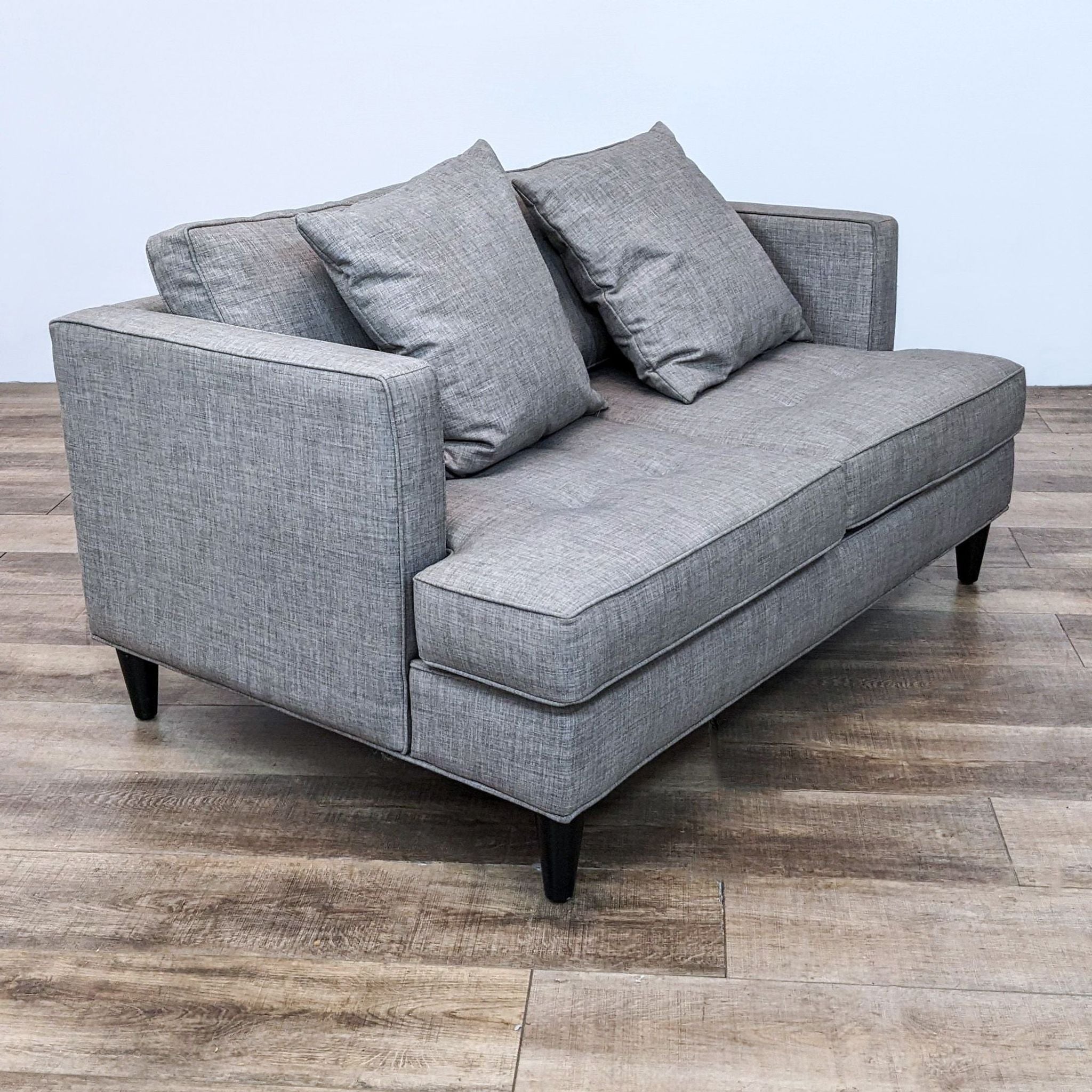 Grey fabric bench seat loveseat by Reperch with narrow arms, tufted design, and dark legs.