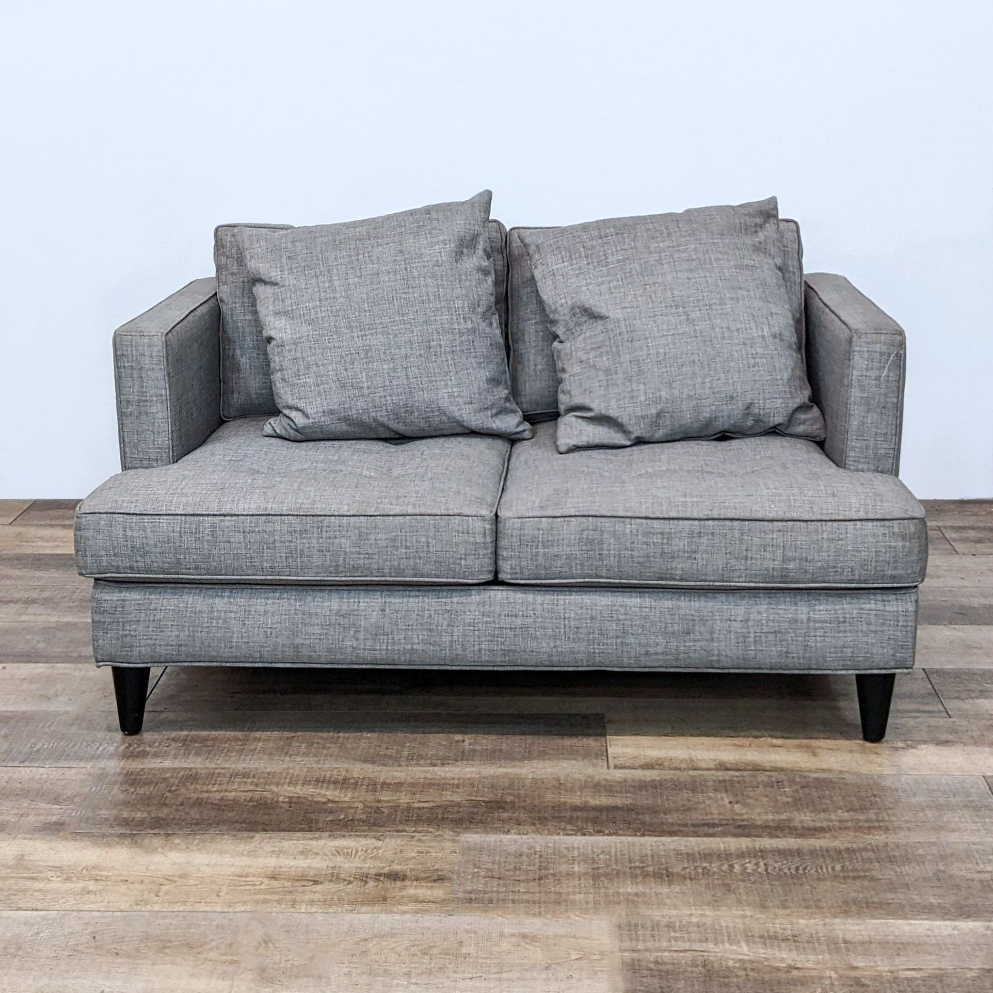 Reperch tufted loveseat with grey upholstery and dark wooden feet, featuring two cushions.