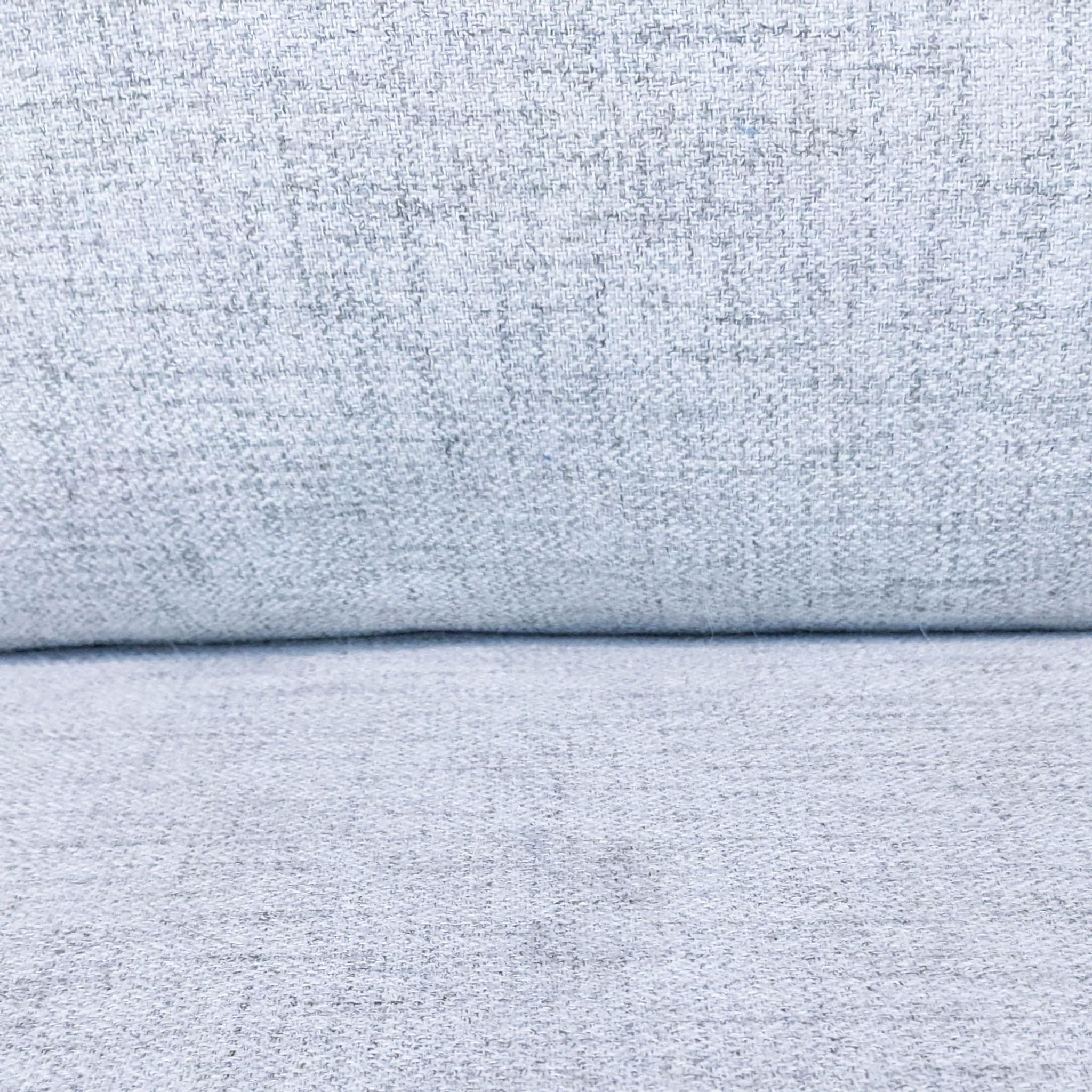Close-up texture of a Reperch 3-seat sofa's gray fabric upholstery.