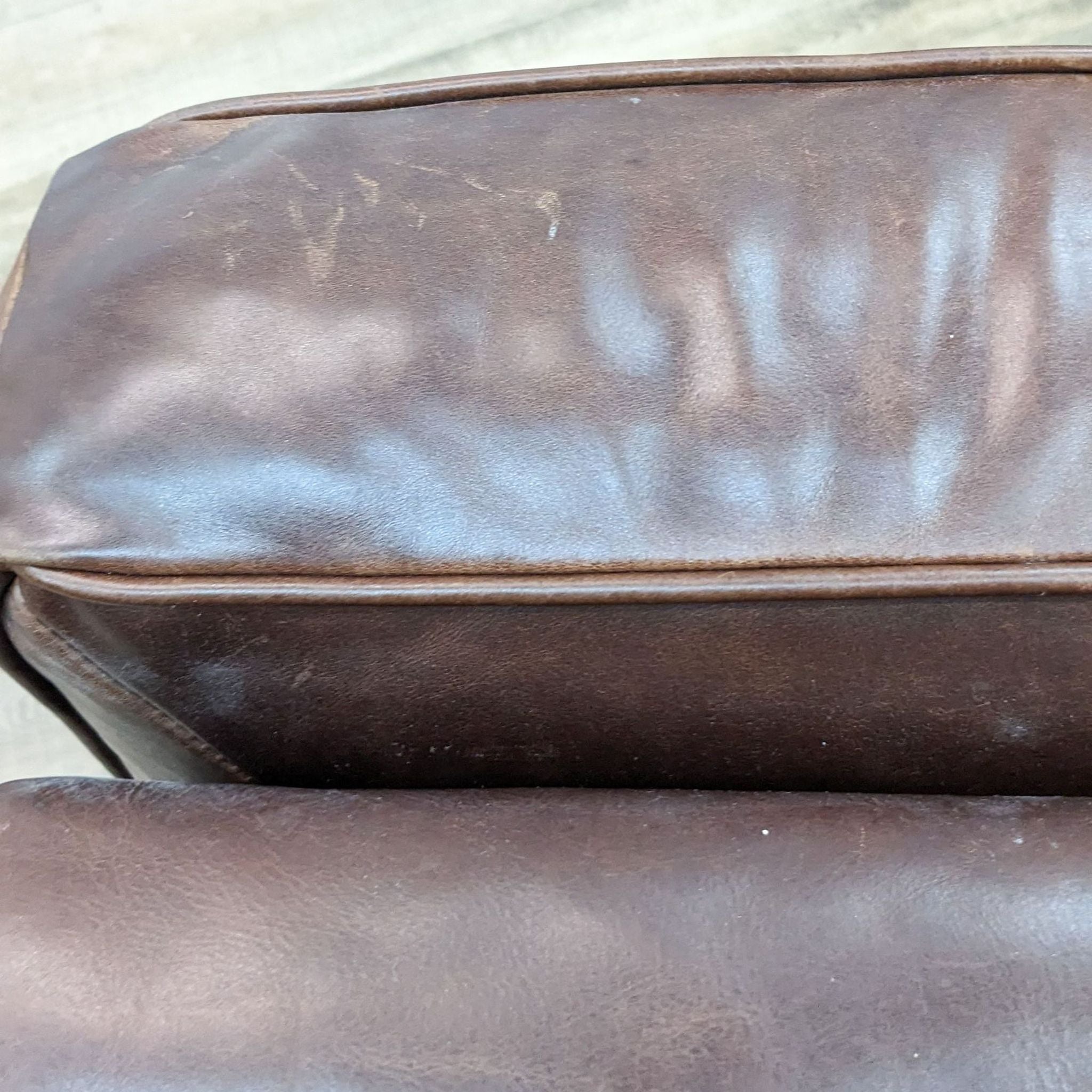 Close-up of a Henredon brown leather ottoman showcasing the texture, nail head detailing, and stitching.