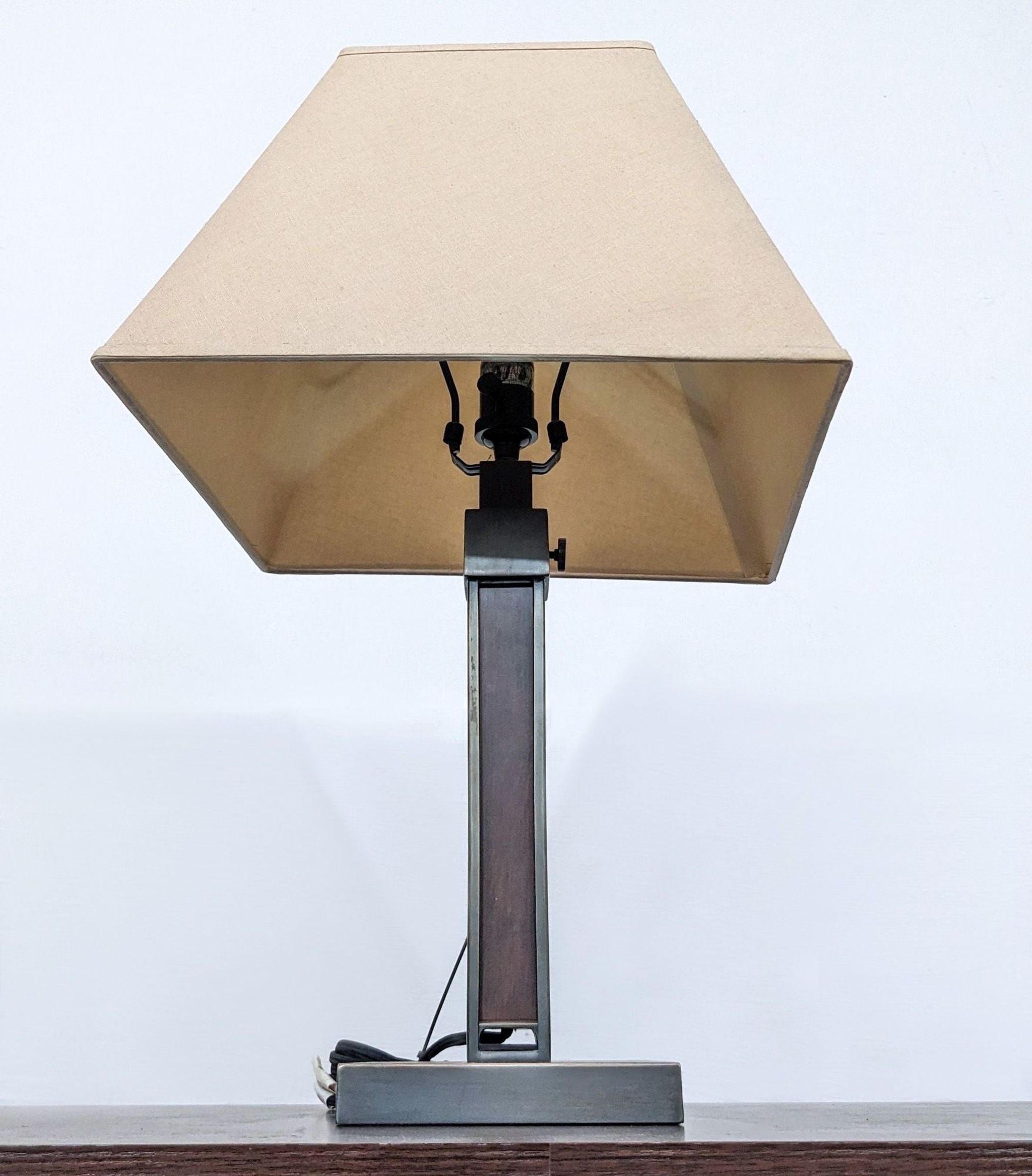 Close-up of Reperch table lamp showing beige lampshade, metallic neck, and base with visible cord and switch.