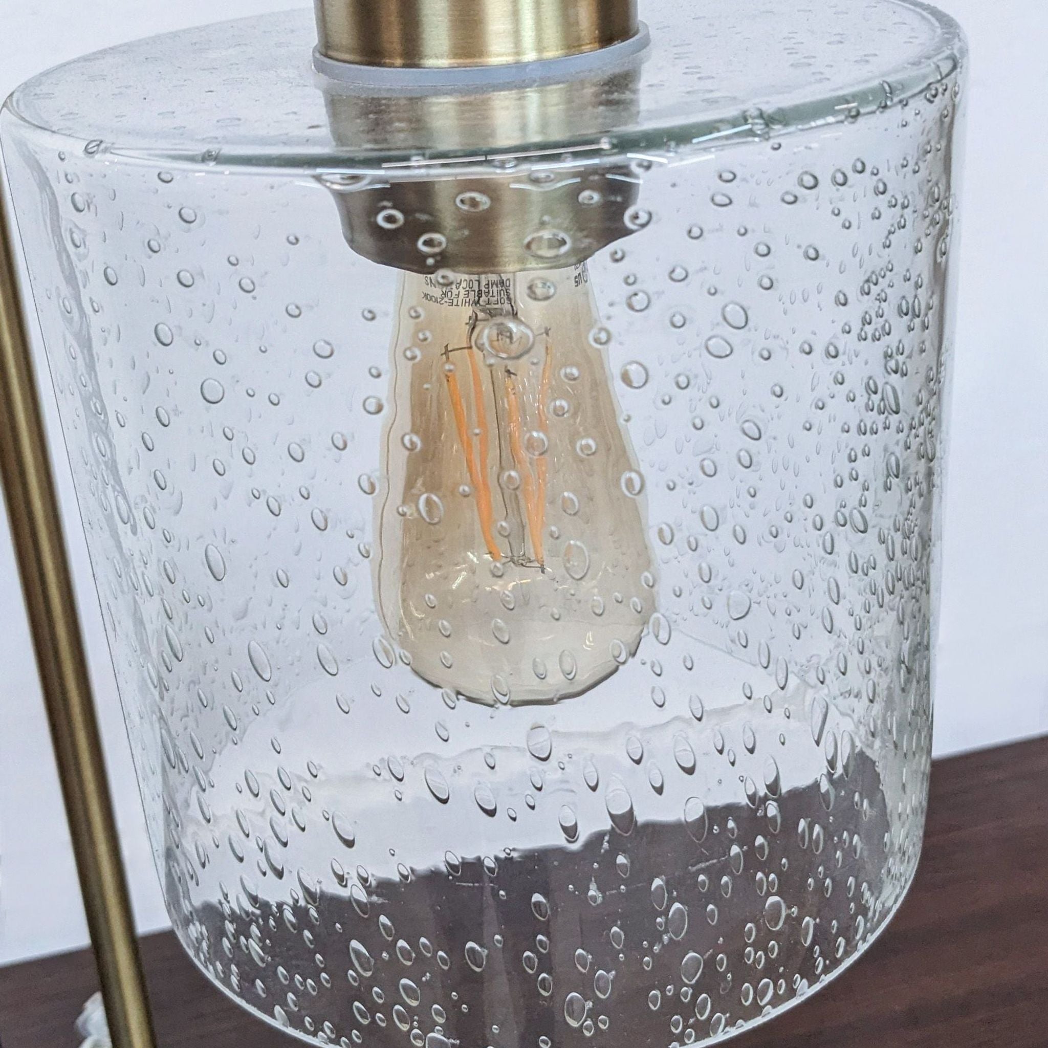 Close-up of Reperch lamp's clear glass shade with water droplet effect and visible bulb, highlighting texture details.