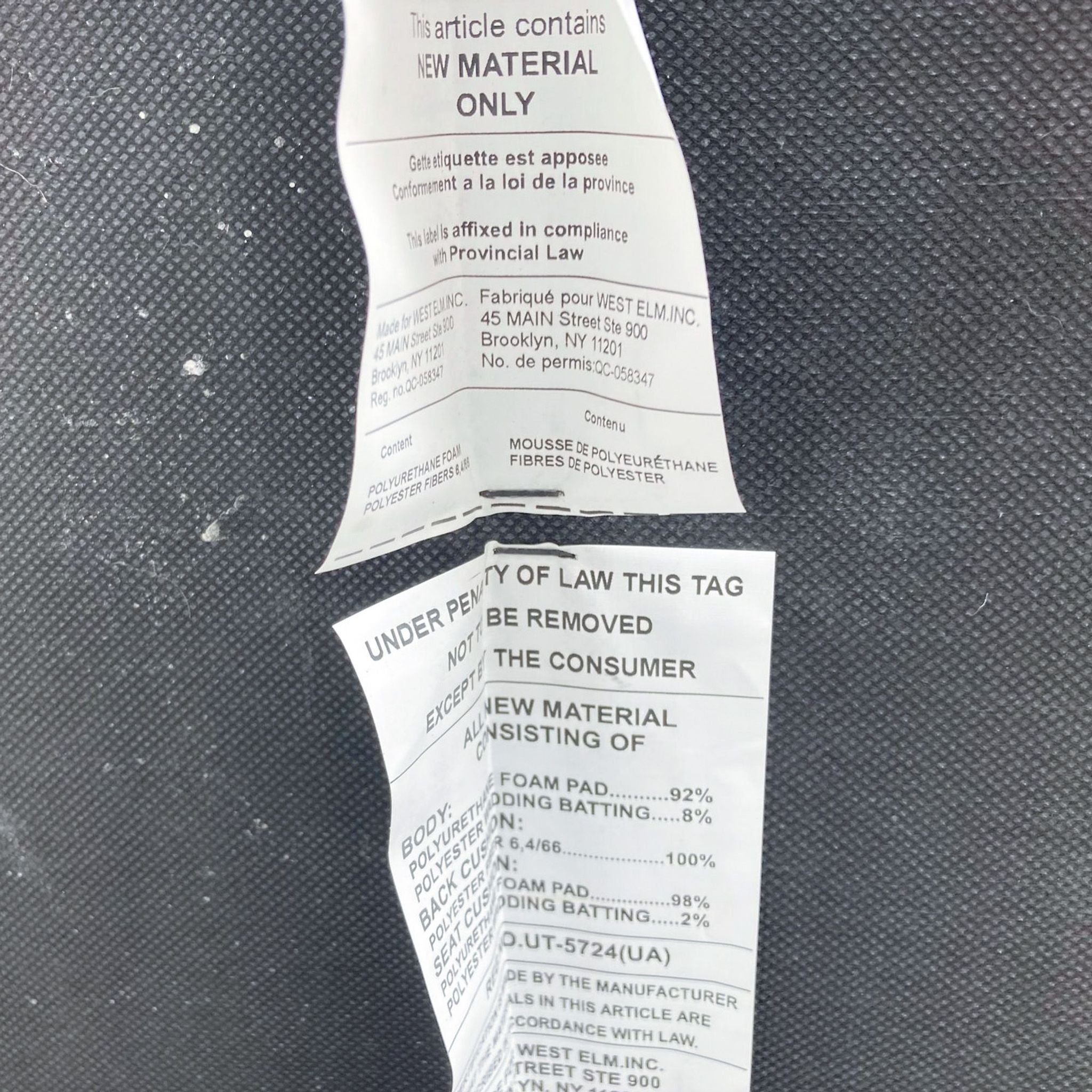 Torn law label tags from a West Elm modern gray heather weave fabric sofa with details about materials and brand information.