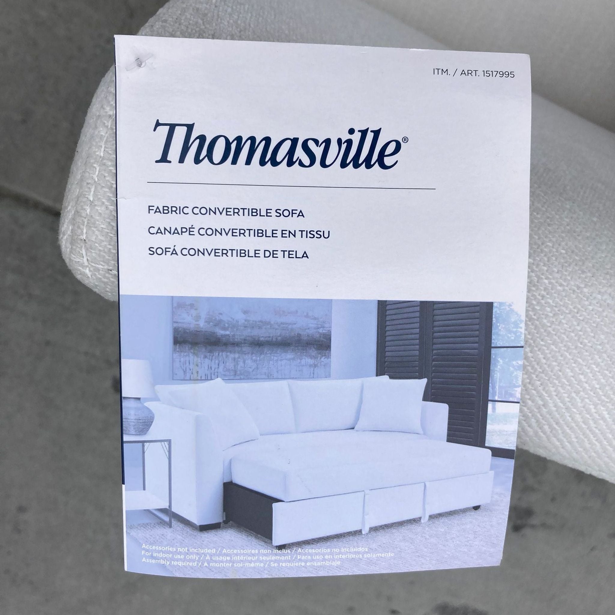 Close-up of a Thomasville tag on a fabric convertible sofa with product details.