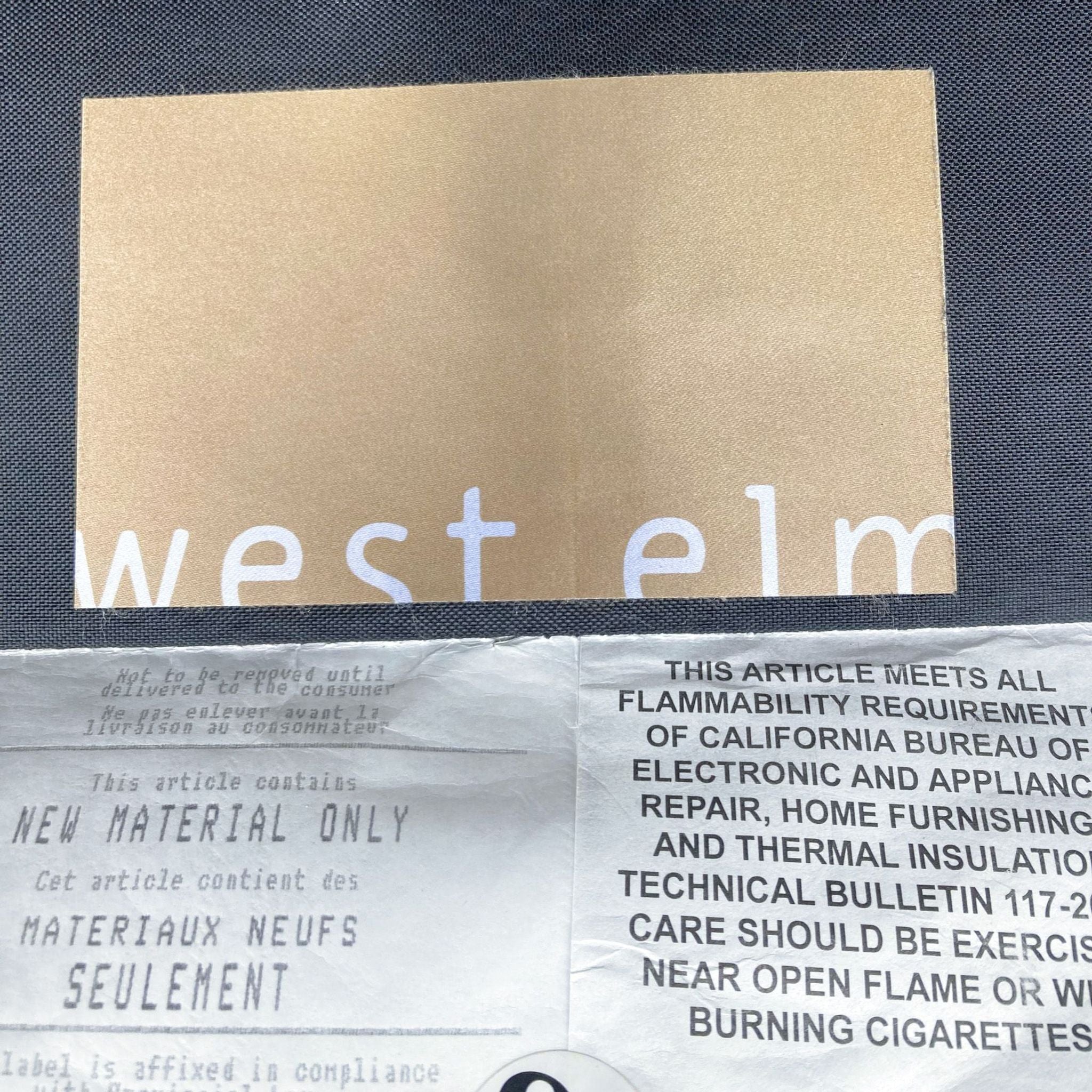 Brand label of West Elm on a linen weave fabric, indicating new material and flammability requirements.