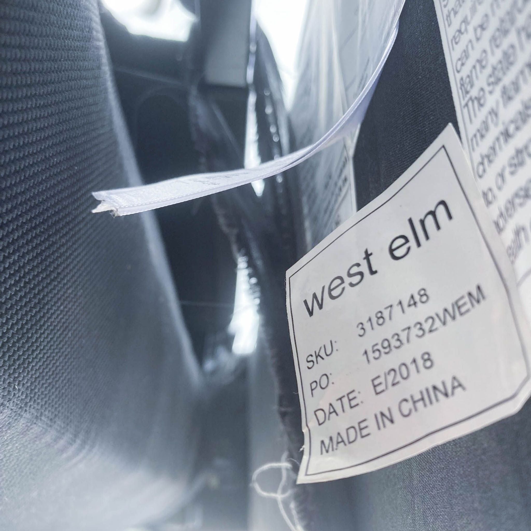 Close-up of a West Elm label on a slate-colored fabric, indicating the brand and item details.