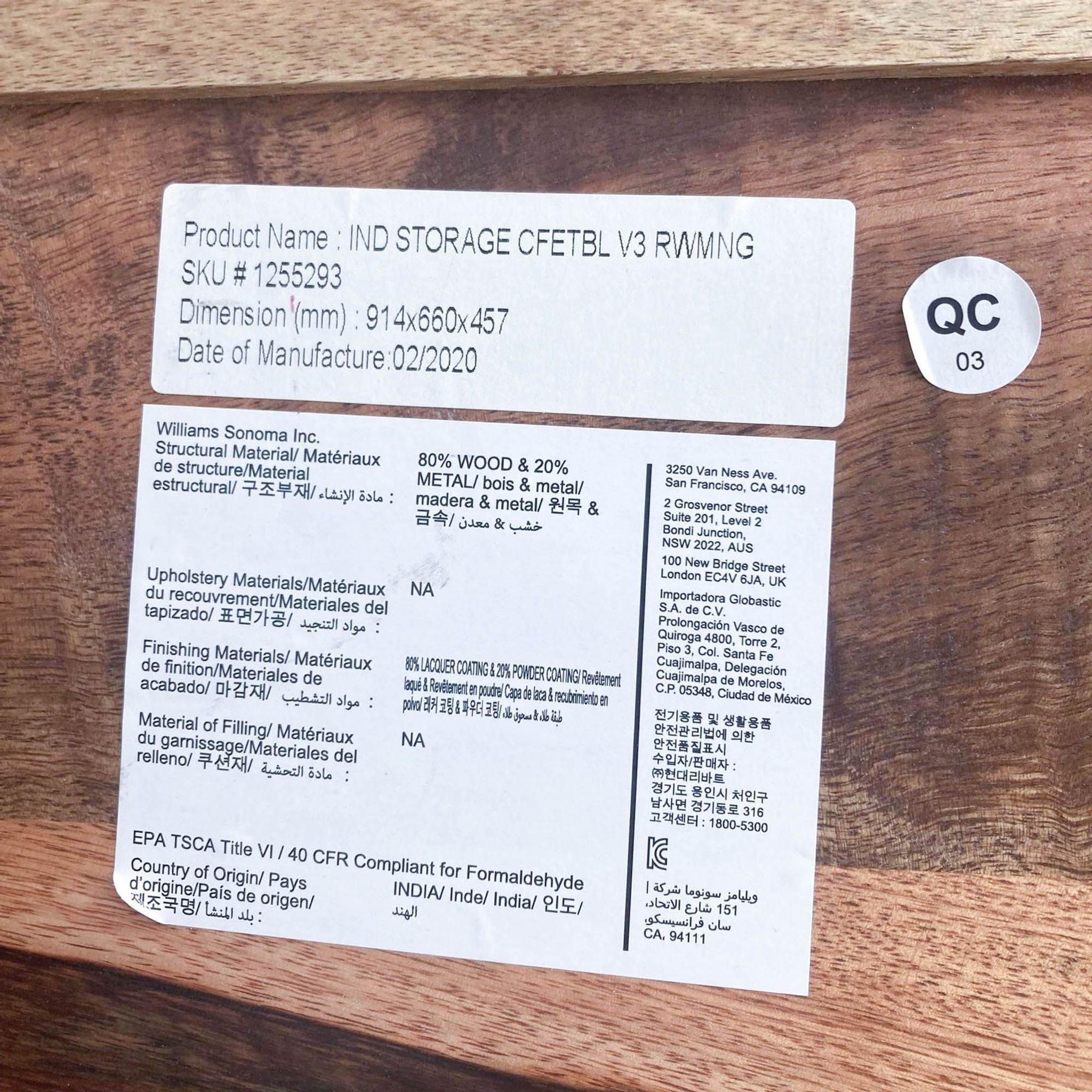 Close-up of manufacturer's label on West Elm mango wood coffee table detailing product name, materials, and origin.