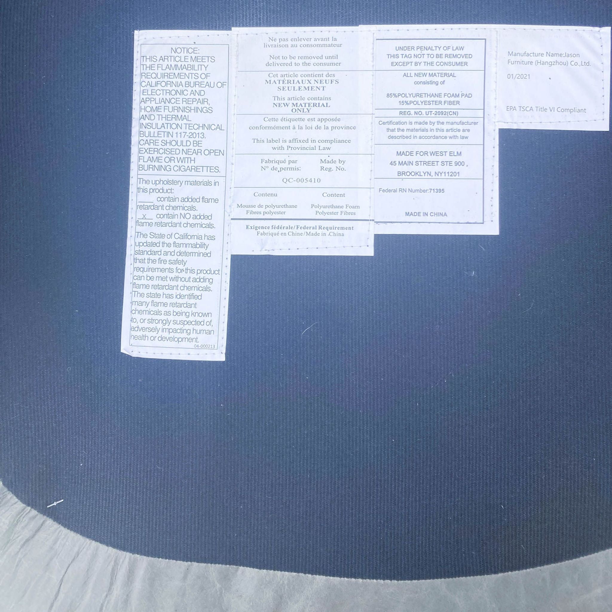 Care label and description tags attached to the West Elm Crescent lounge chair, detailing materials and compliance info.