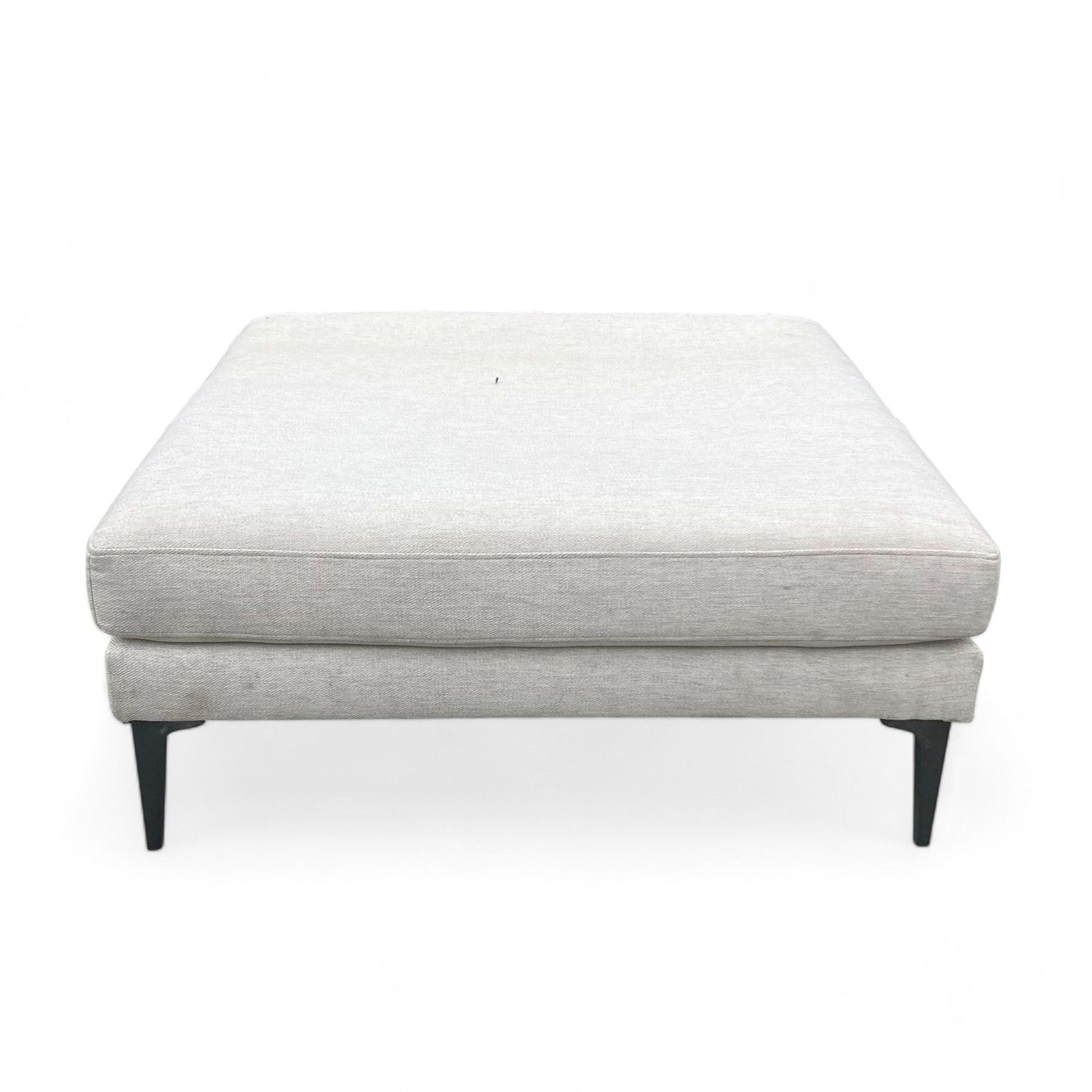 Alt text 1: West Elm modern Andes large square ottoman with wheat twill fabric upholstery and dark pewter metal legs.