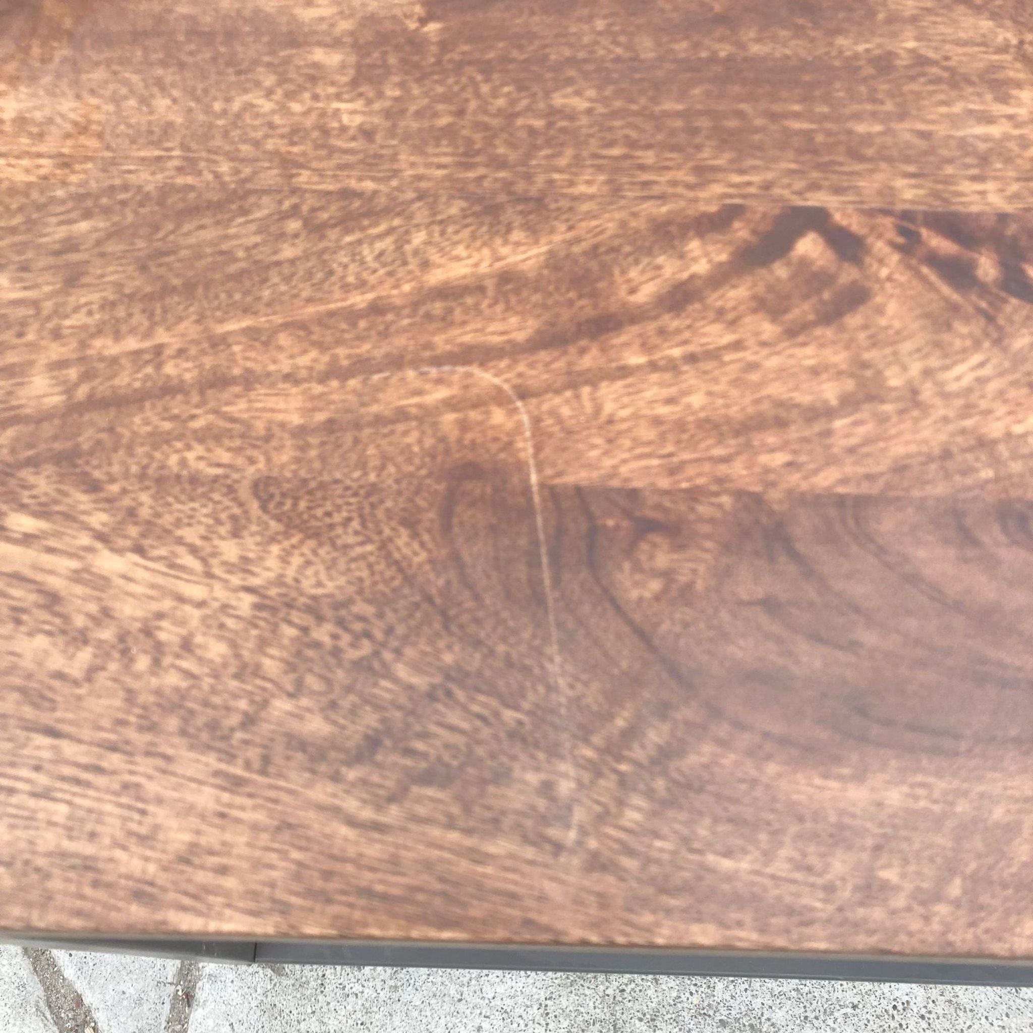 Close-up of the walnut-finished mango wood top of a West Elm coffee table.