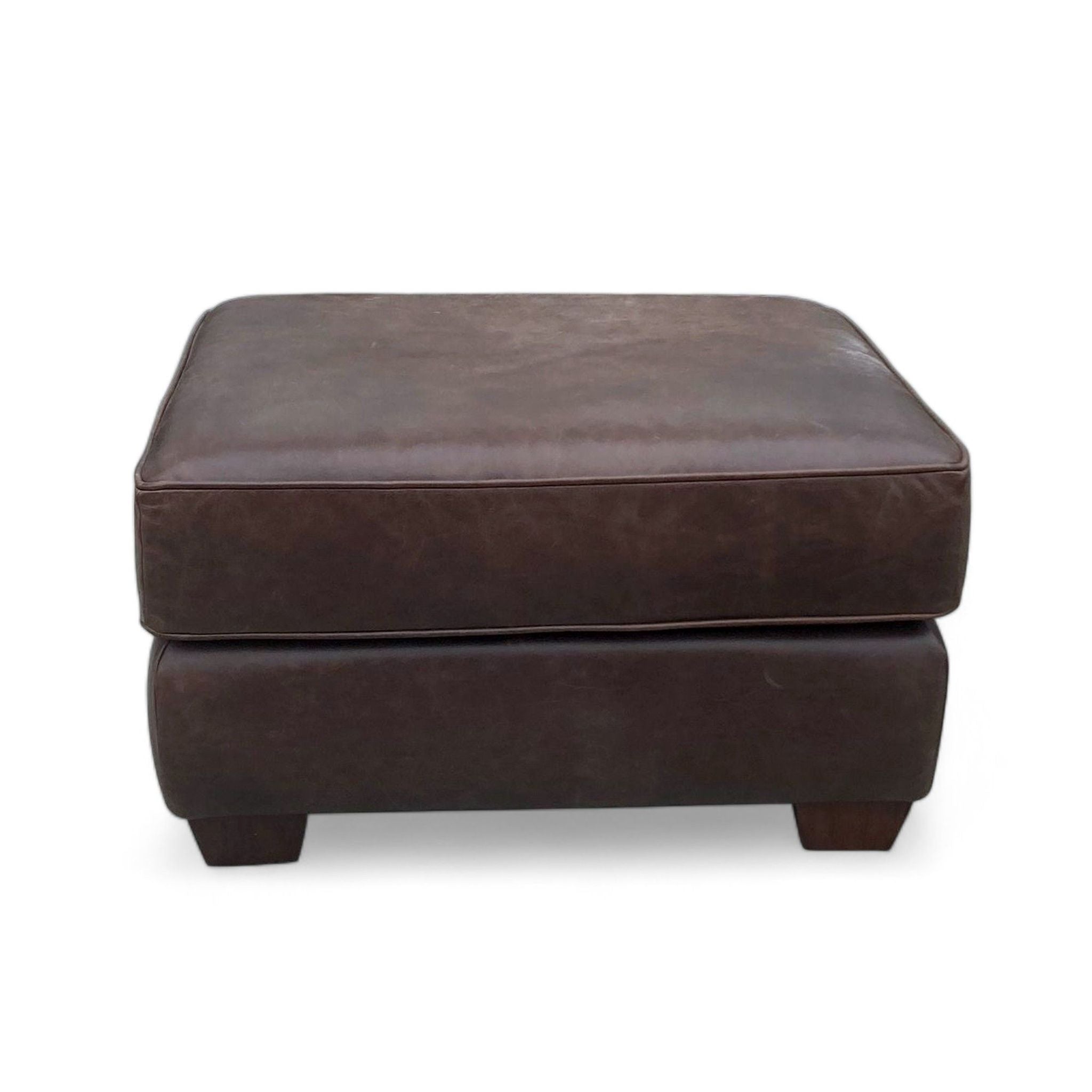 1. "Pottery Barn's Pearce Ottoman in brown leather with dark wood feet, shown against a neutral background."