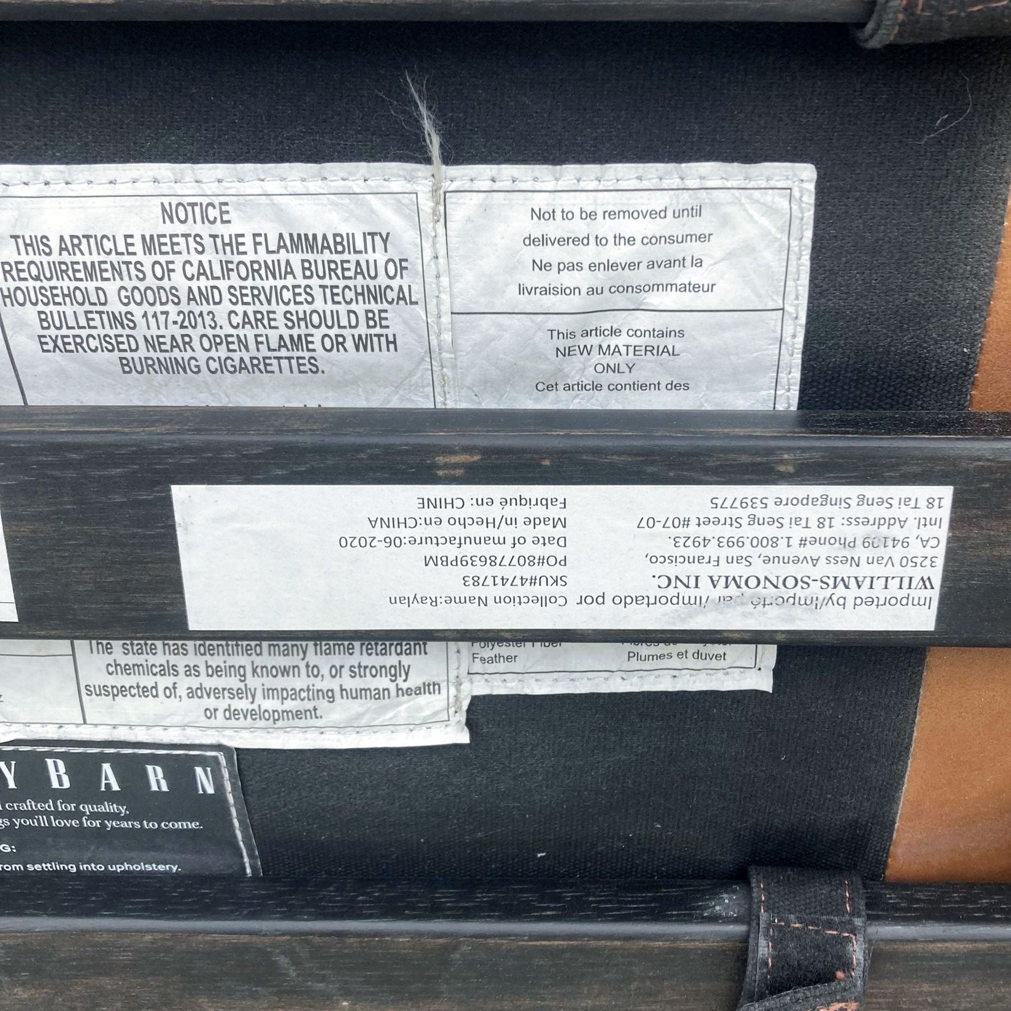 3. "Underside view of a Pottery Barn leather ottoman displaying product information and care labels."