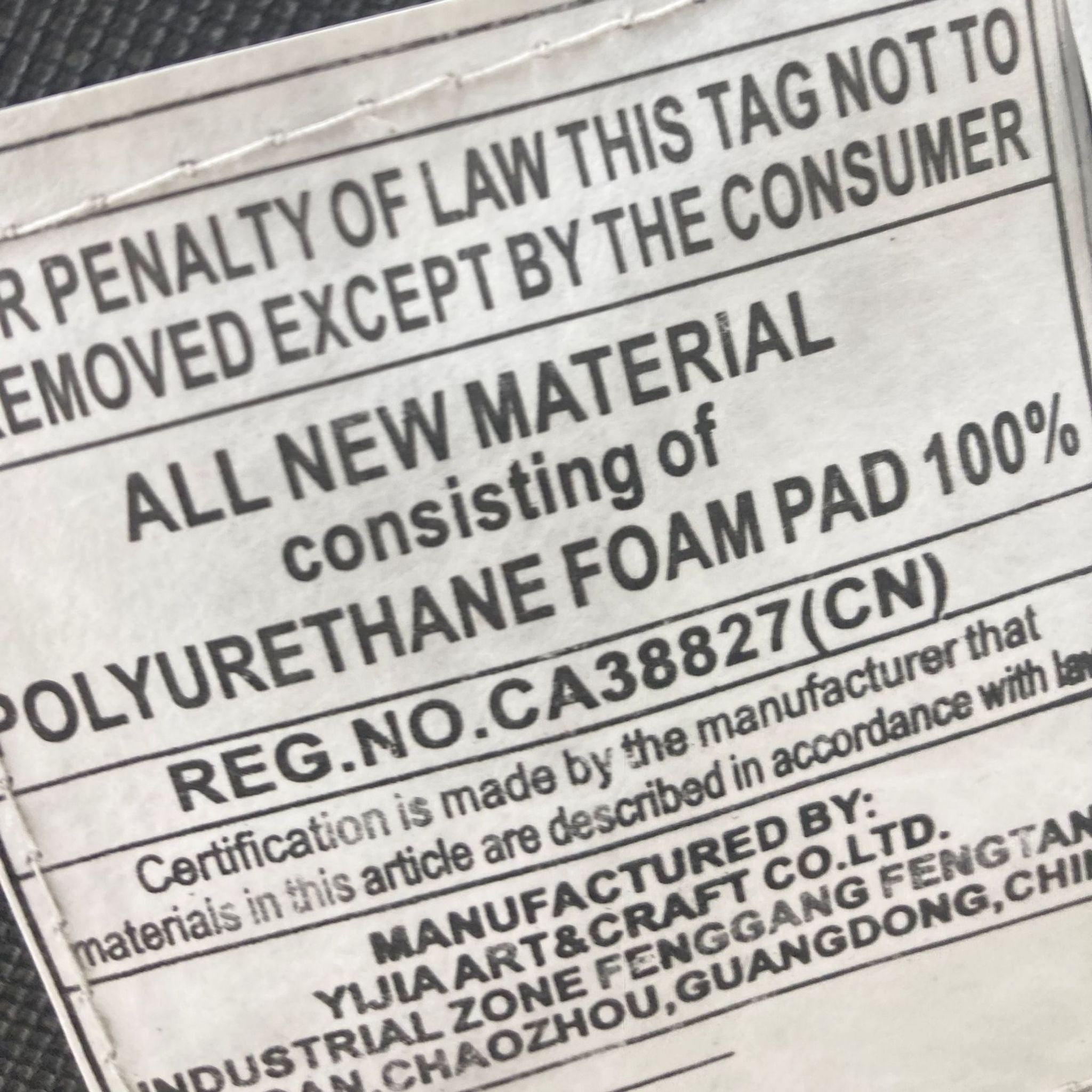 Close-up of the regulatory label on a Target brand storage ottoman indicating material and manufacturer details.
