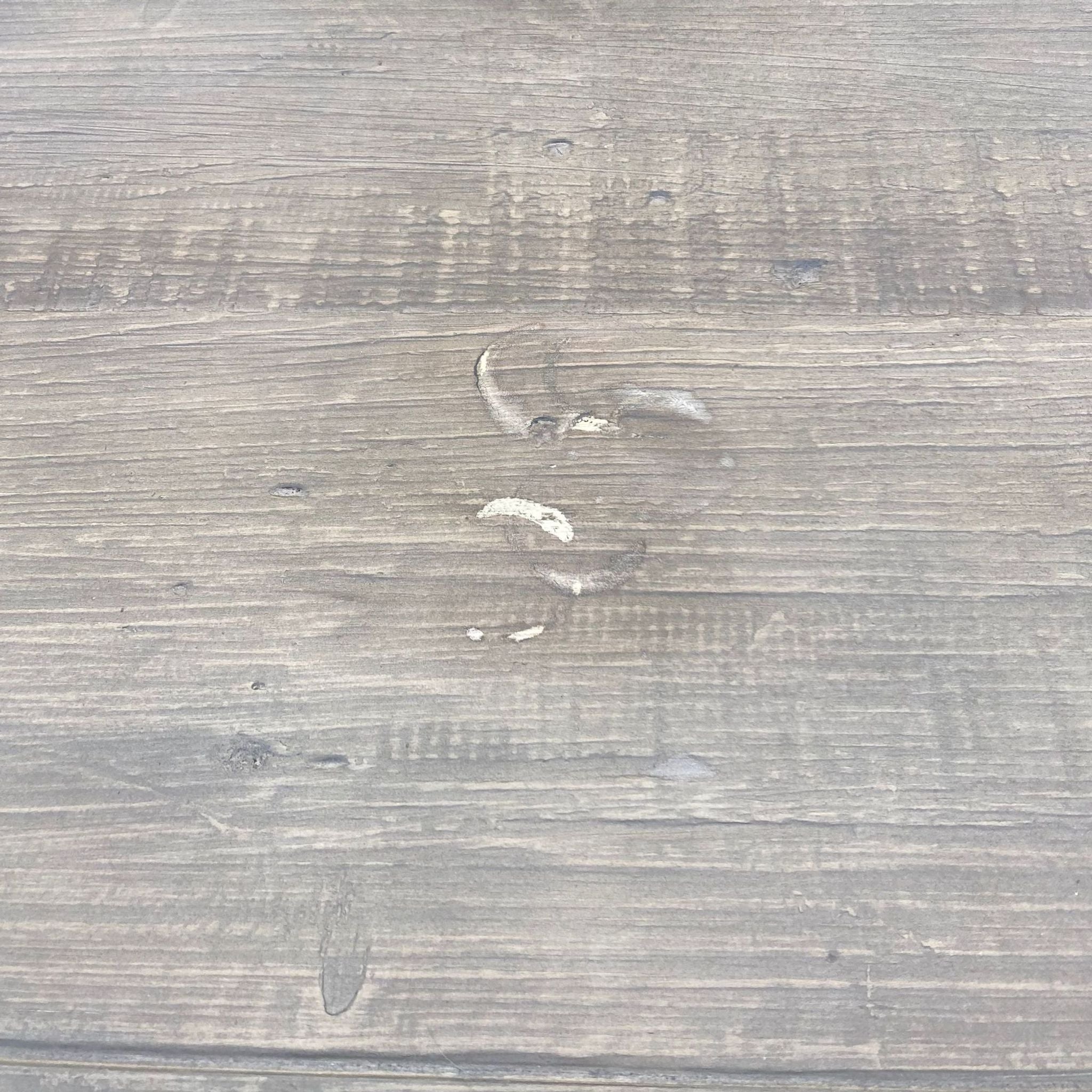 Close-up of the wooden tabletop with a noticeable white scuff mark, showing signs of wear.