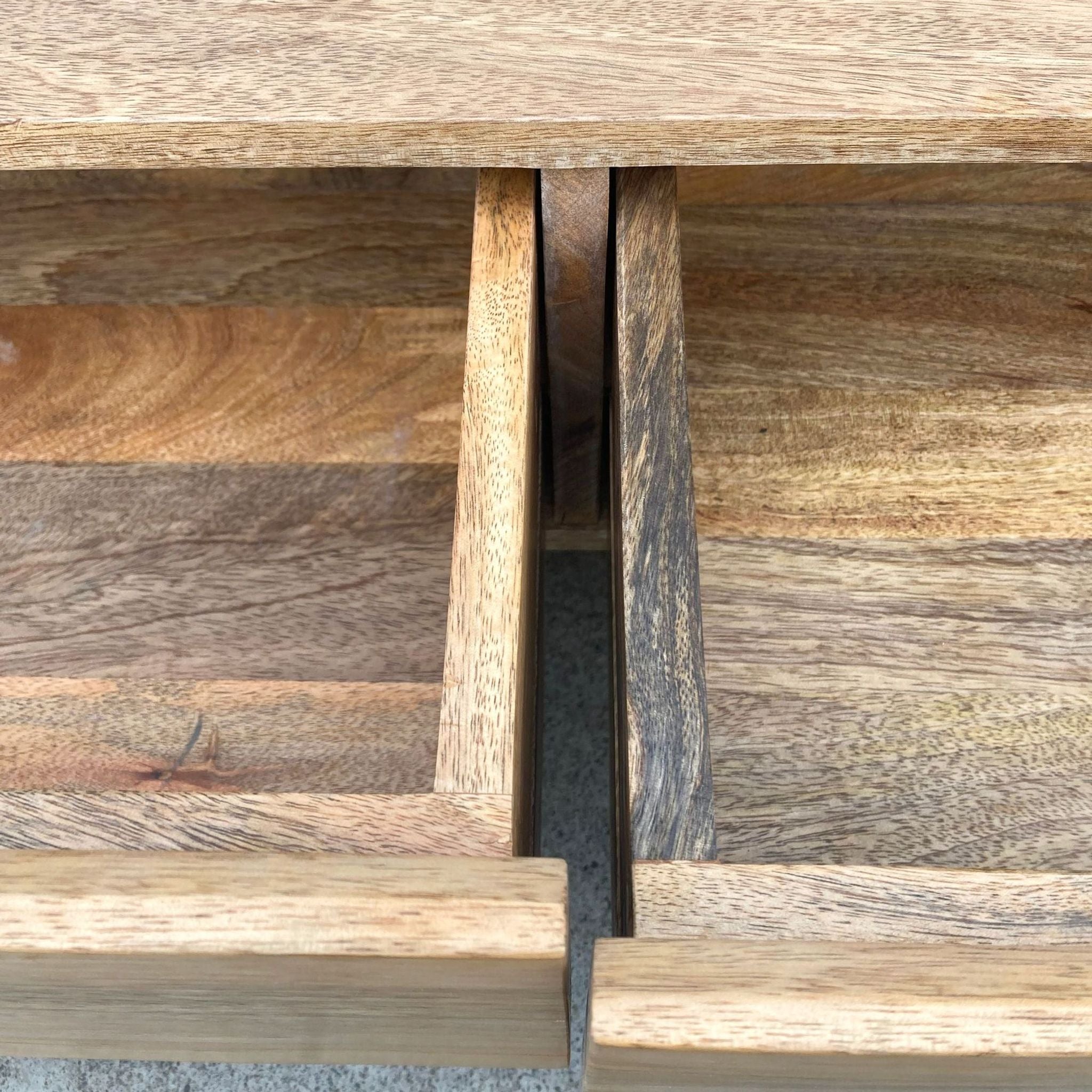 Close-up of mango wood shelf and drawer detail on a West Elm side table with steel supports.