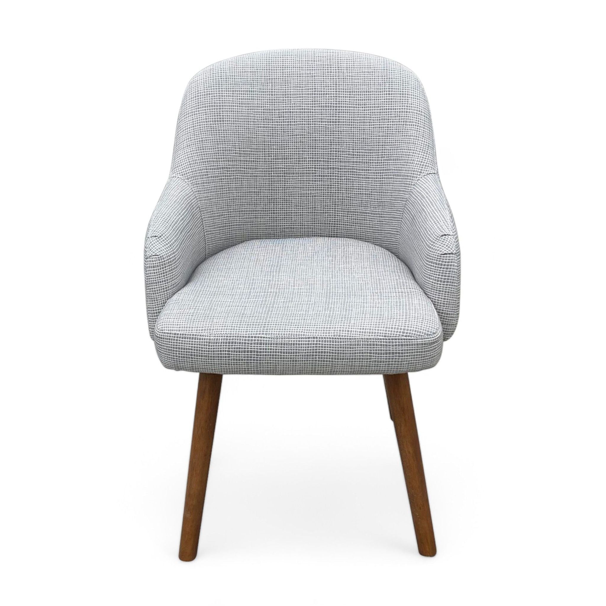 West Elm dining chair with a gray upholstered barrel back seat and solid wood legs.