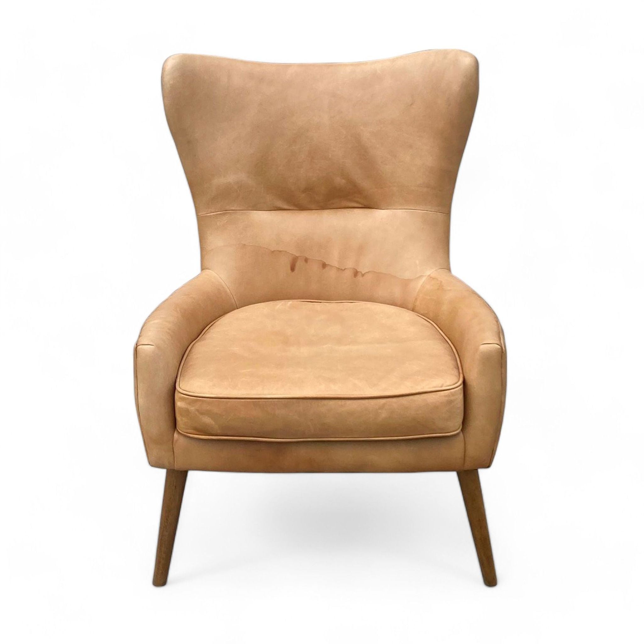 Tan leather lounge chair by West Elm with angled wooden legs and a high backrest.
