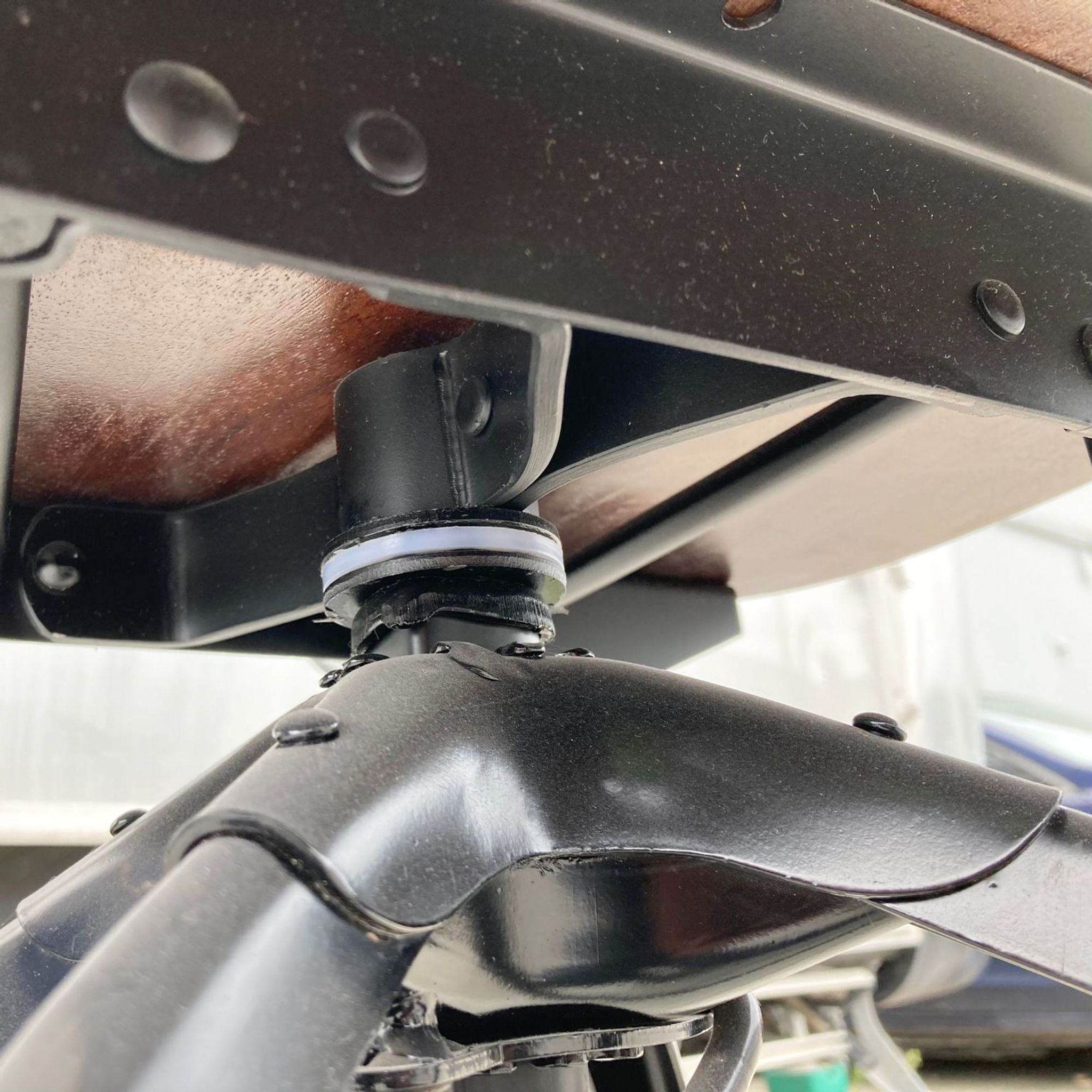 2. Close-up of the swivel mechanism under the wooden seat of a Reperch industrial stool, showing metal parts and screws.