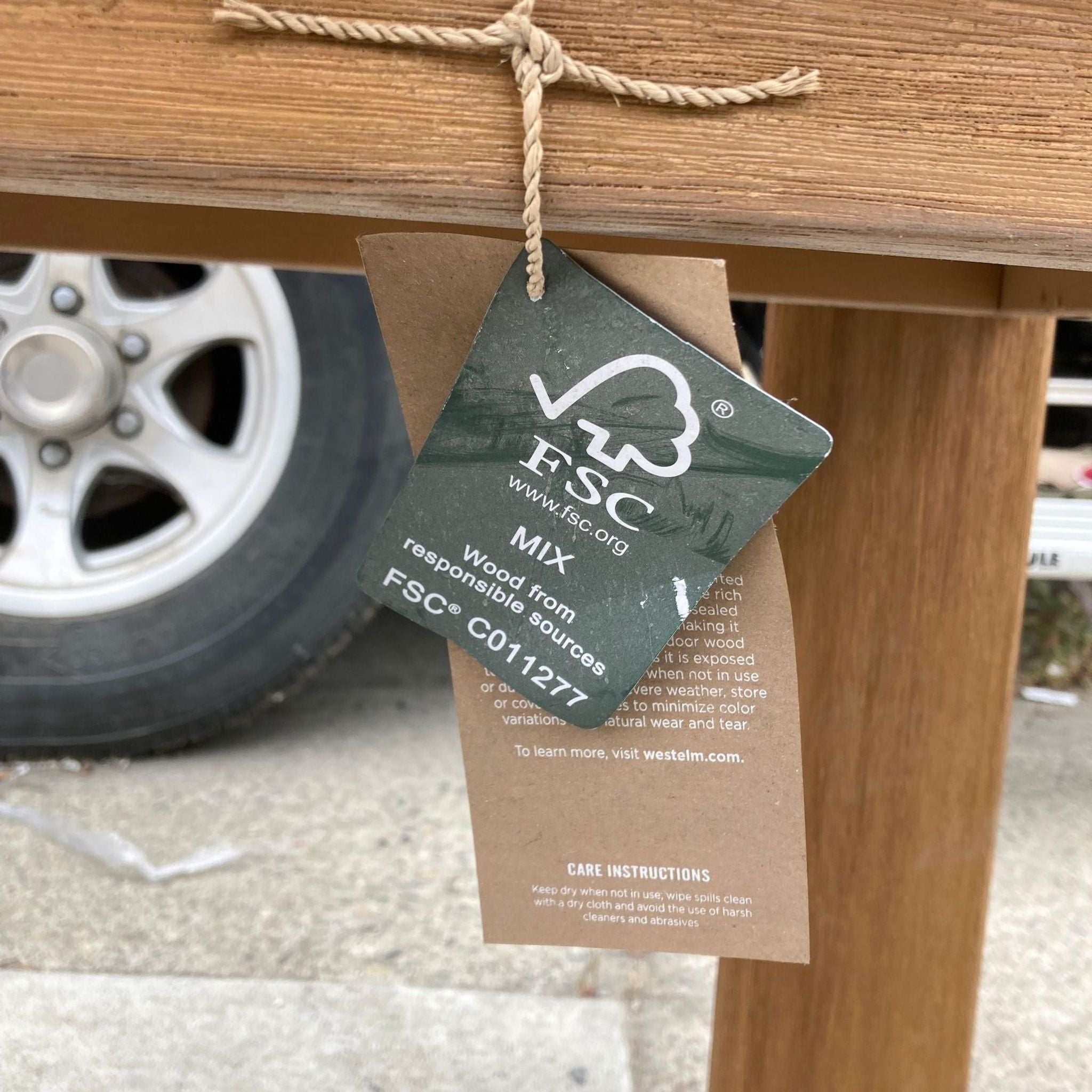 2. Alt-text: Close-up of responsible sourcing tag on wooden West Elm Playa side table, showcasing FSC certification.