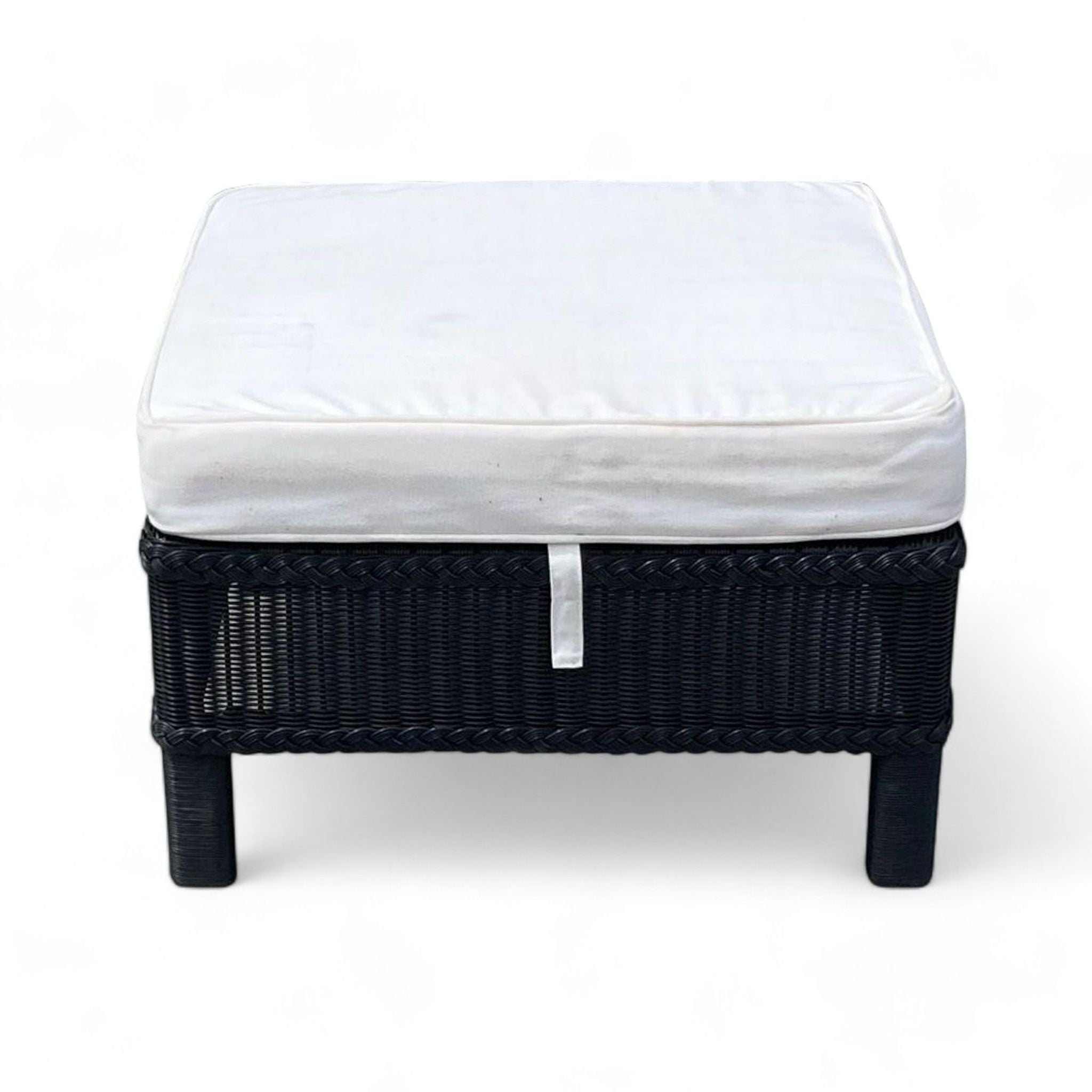 Square ottoman by Reperch with a white cushion on top and a black woven wicker base. Category: Stools, Ottomans & Benches.
