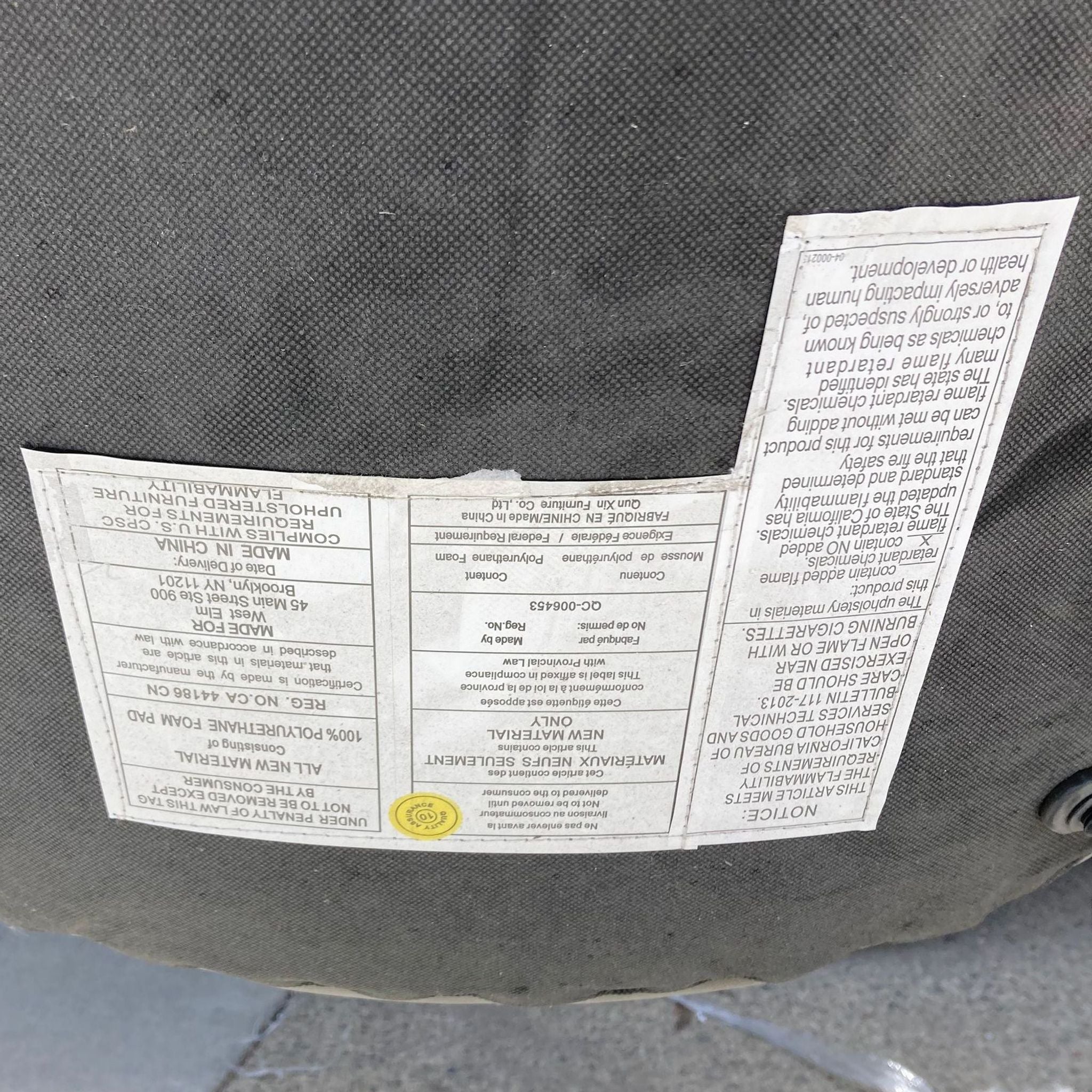 3. "Underneath view of the Slope dining chair by West Elm, showing the care label and black textile bottom cover."