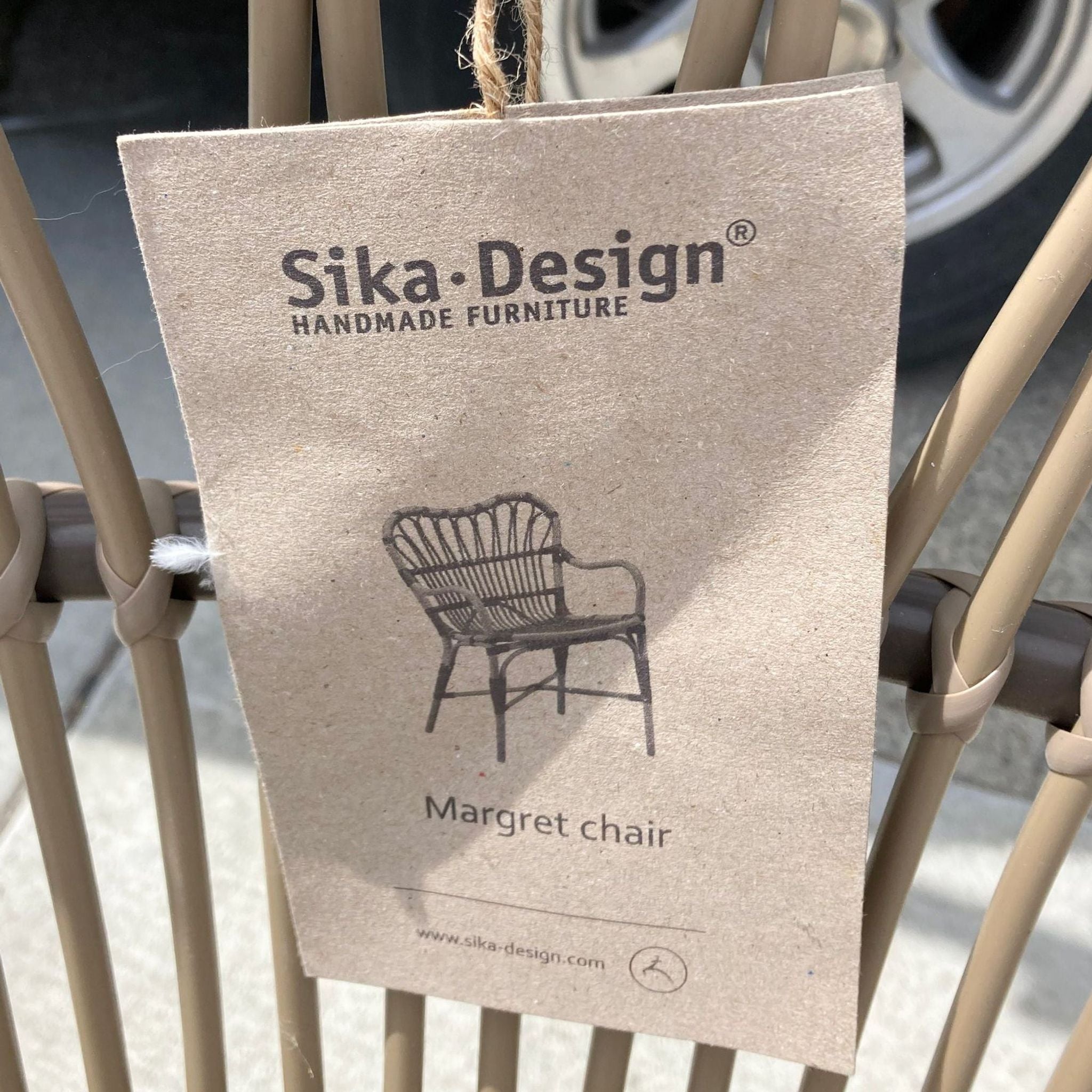 Close-up of a Sika Design tag attached to a Margaret chair, highlighting the brand's handmade furniture and the chair's design name.
