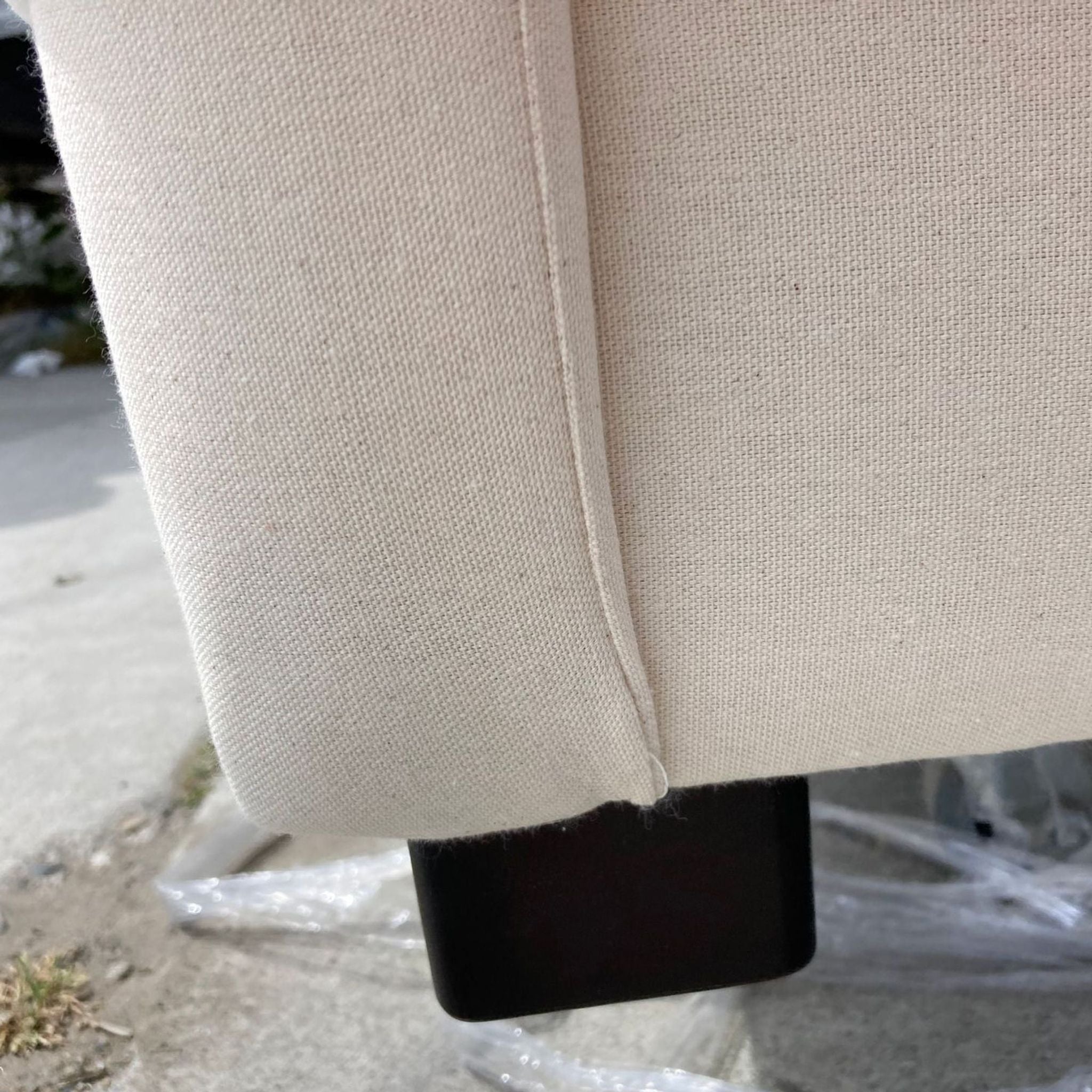 Close-up of a lounge chair leg with neutral upholstery, highlighting the fabric texture and dark wood finish.