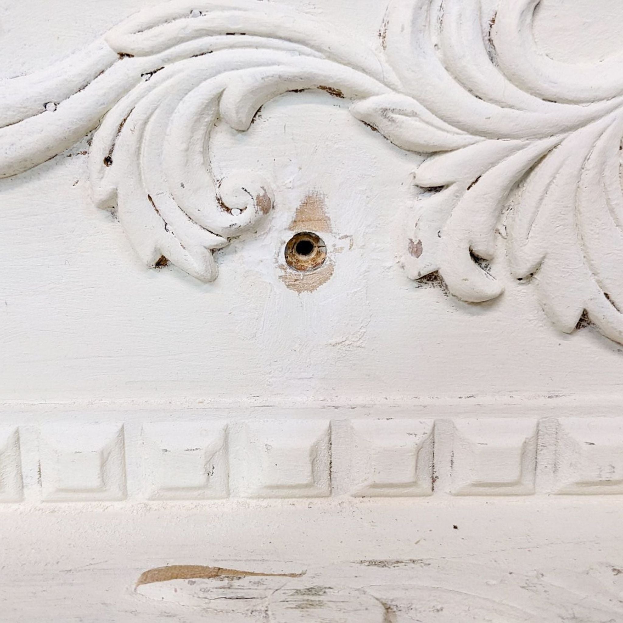 Detailed image showcasing the carved accents and dental molding on a Victorian-style wooden frame with a white distressed finish.