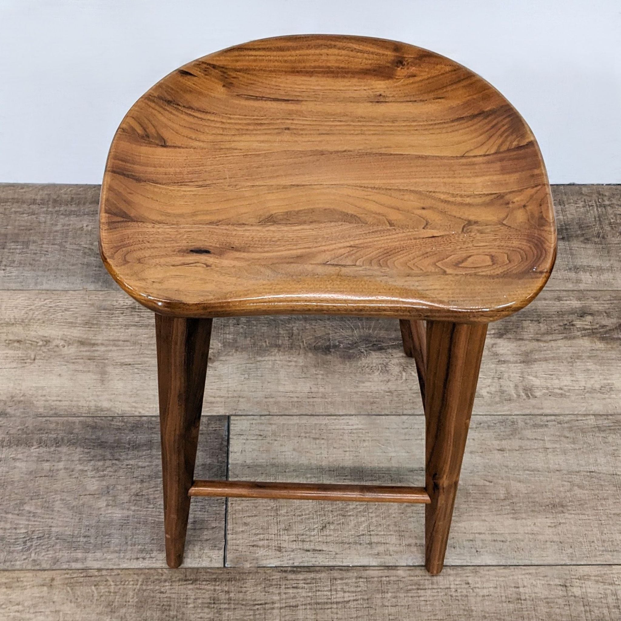 2. Overhead view of a Rejuvenation wooden stool with a curved seat, showcasing its wood grain and finish.