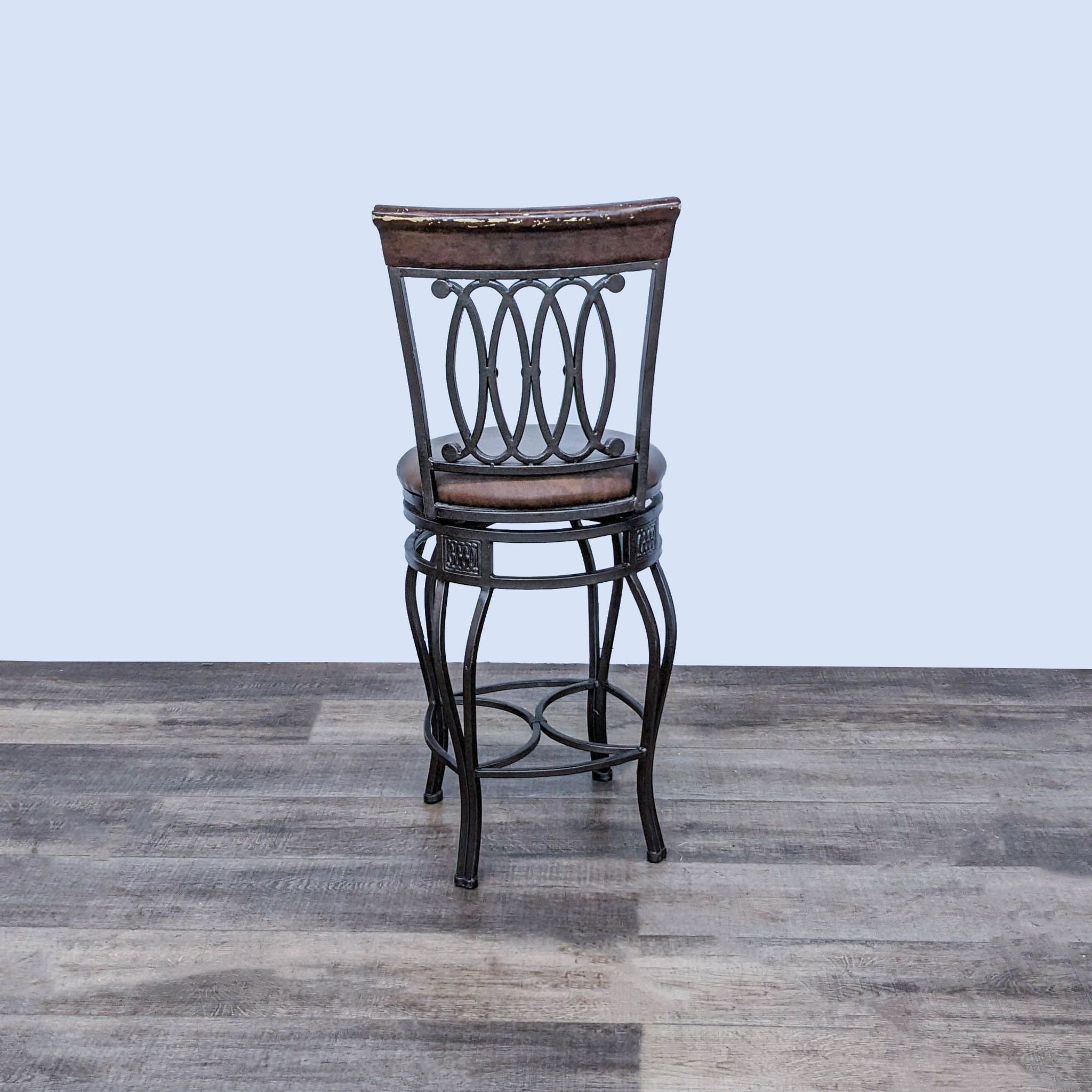 Reperch swivel barstool featuring a padded seat, intricate metal base, and wooden back on a plank floor.