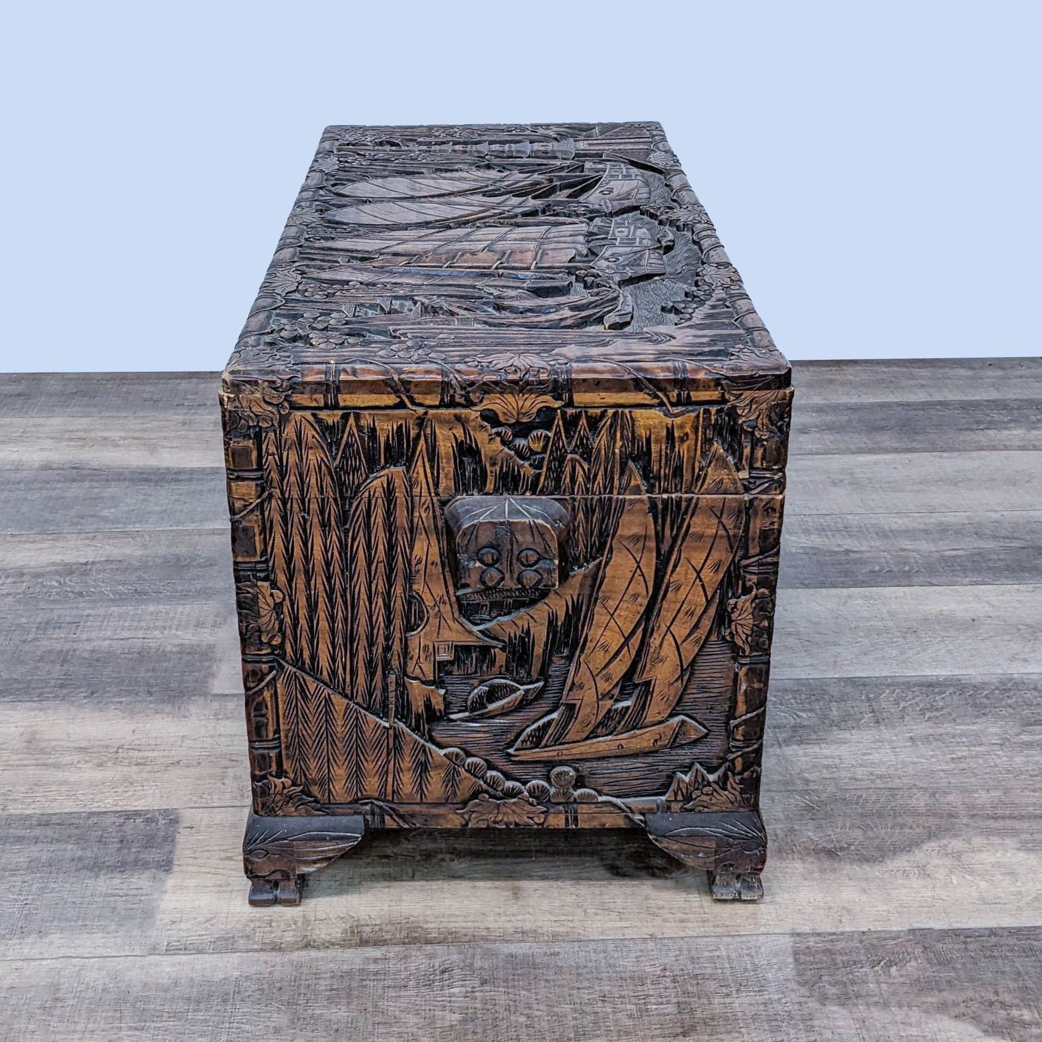 Antique-style Reperch trunk featuring detailed maritime carvings on its sides and top, positioned end-on.