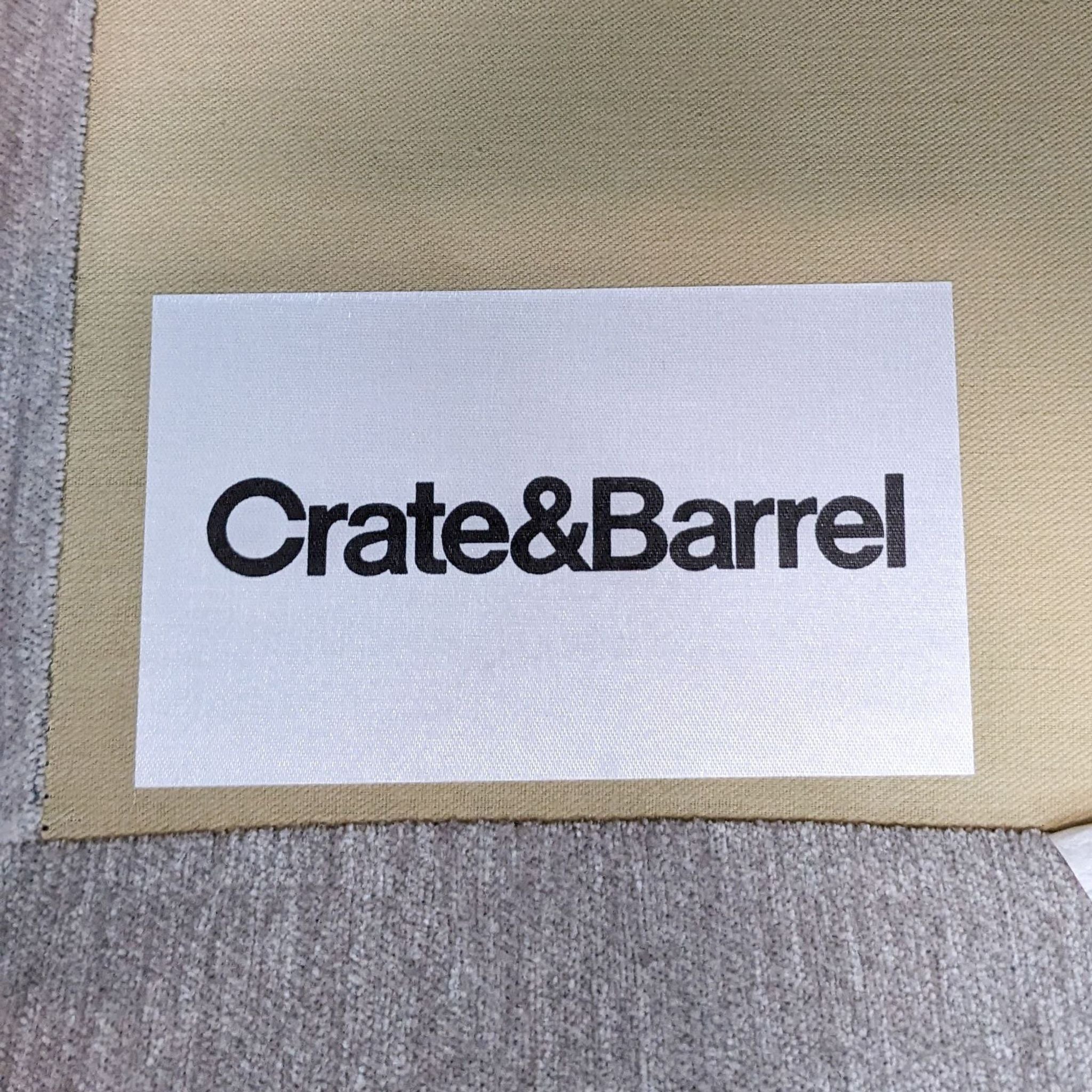 3. Crate & Barrel branding logo on a label with a grey upholstered sofa background, representing modern furniture style.