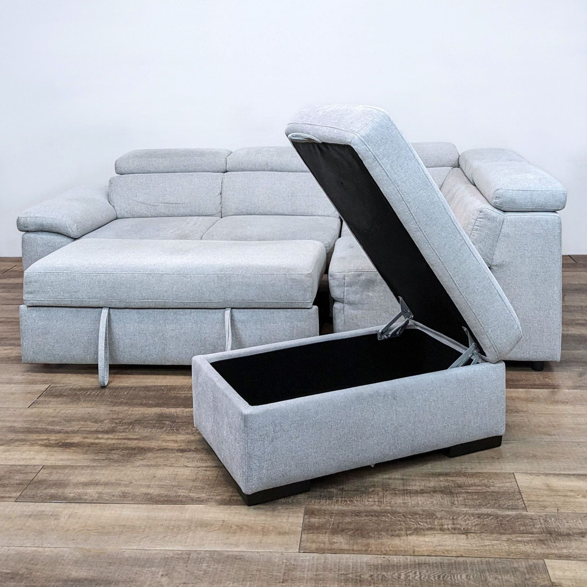 2. Open storage ottoman matching the Reperch light gray sectional, showcasing interior storage space, with the sectional's pull-out chaise visible.