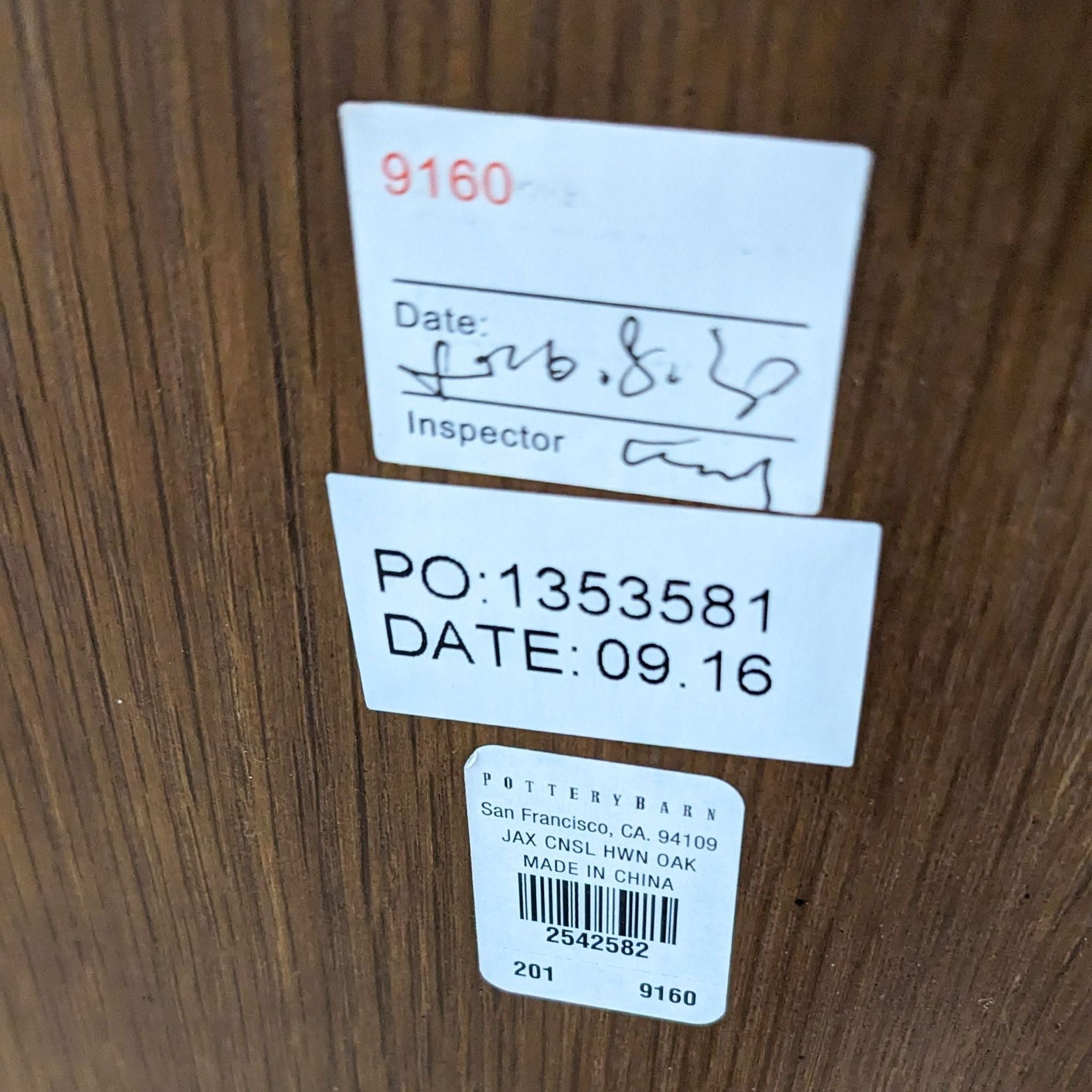 Close-up of Pottery Barn furniture label on wooden surface with inspection details and product information.