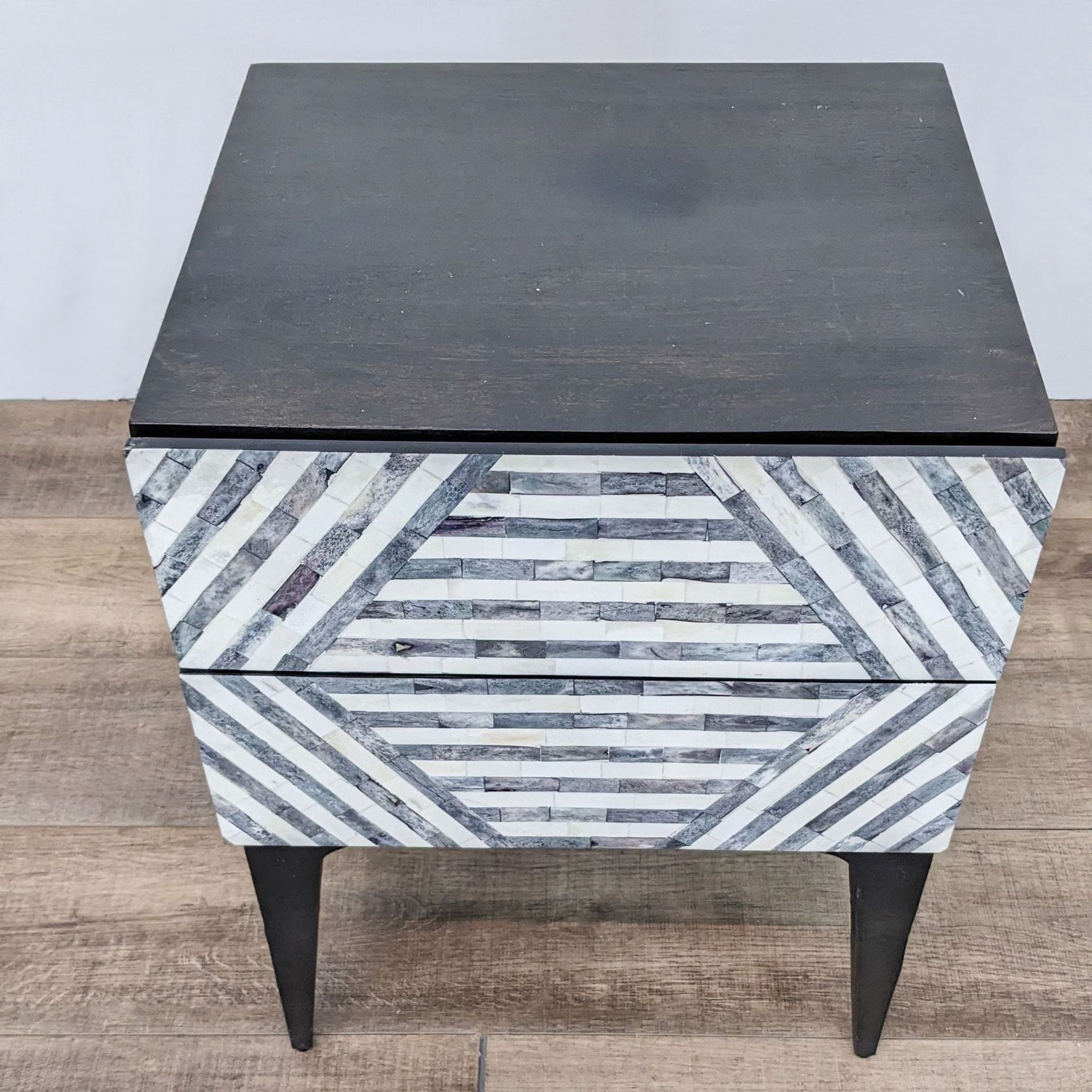 3. Angled perspective of a West Elm end table with a contrasting striped design on two drawers and solid top.
