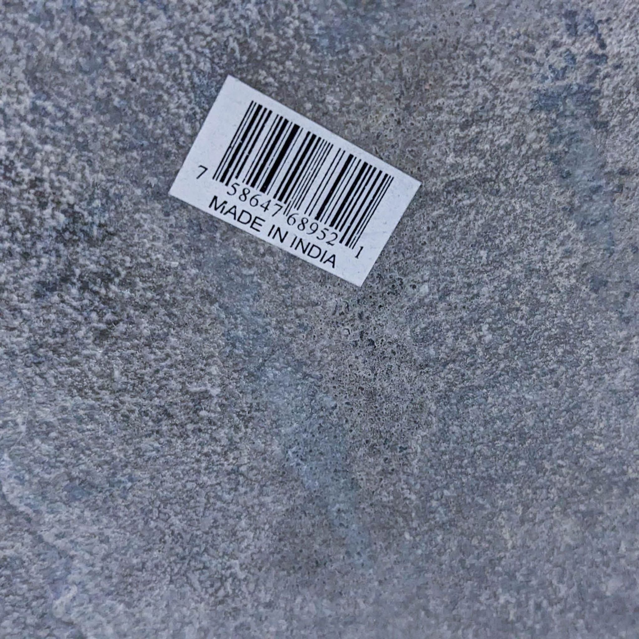 Close-up of a label on the Reperch end table's metallic surface stating "Made in India" with a barcode above the text.
