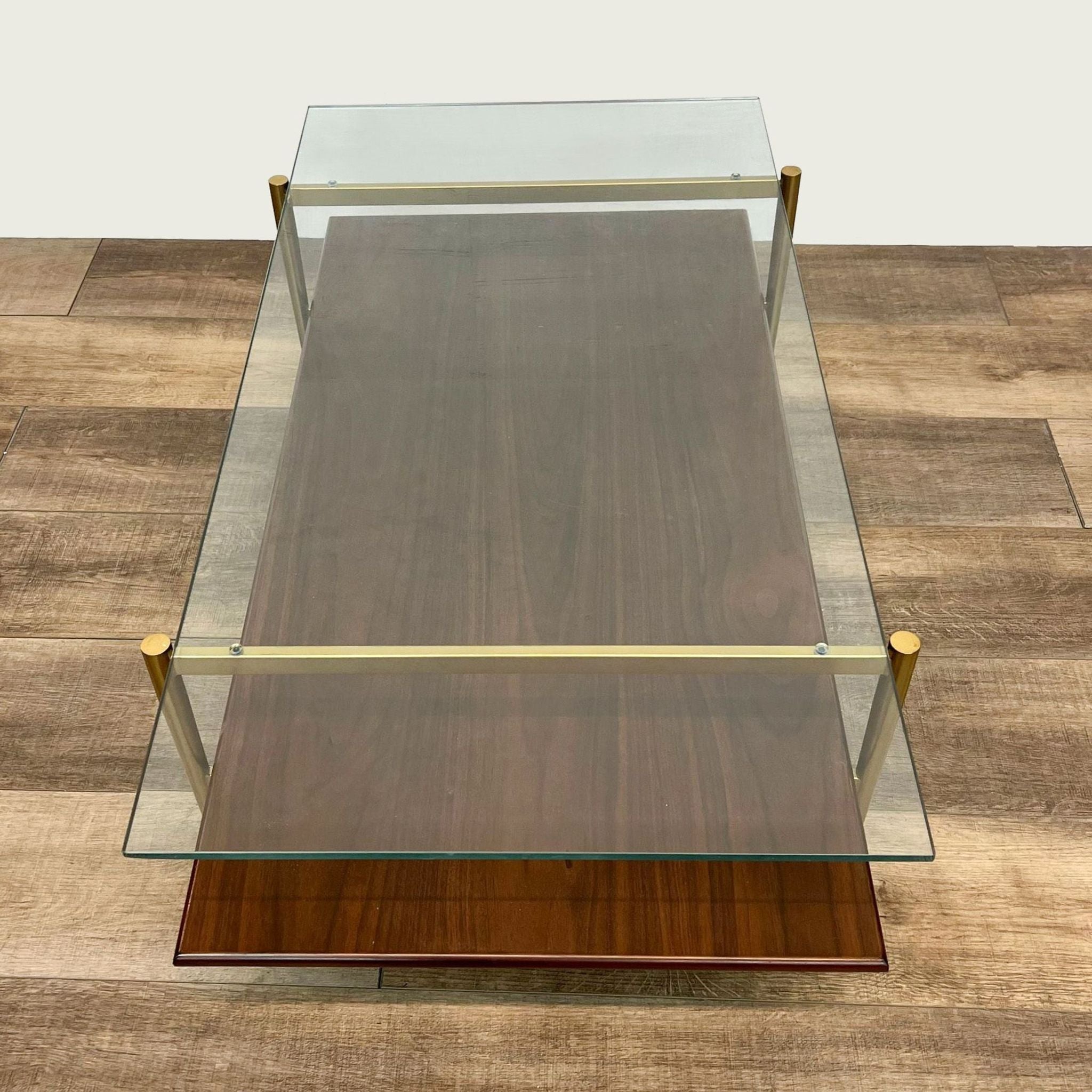 Overhead view of a West Elm/Williams Sonoma two-tier coffee table with a clear glass upper surface and walnut wood underneath.