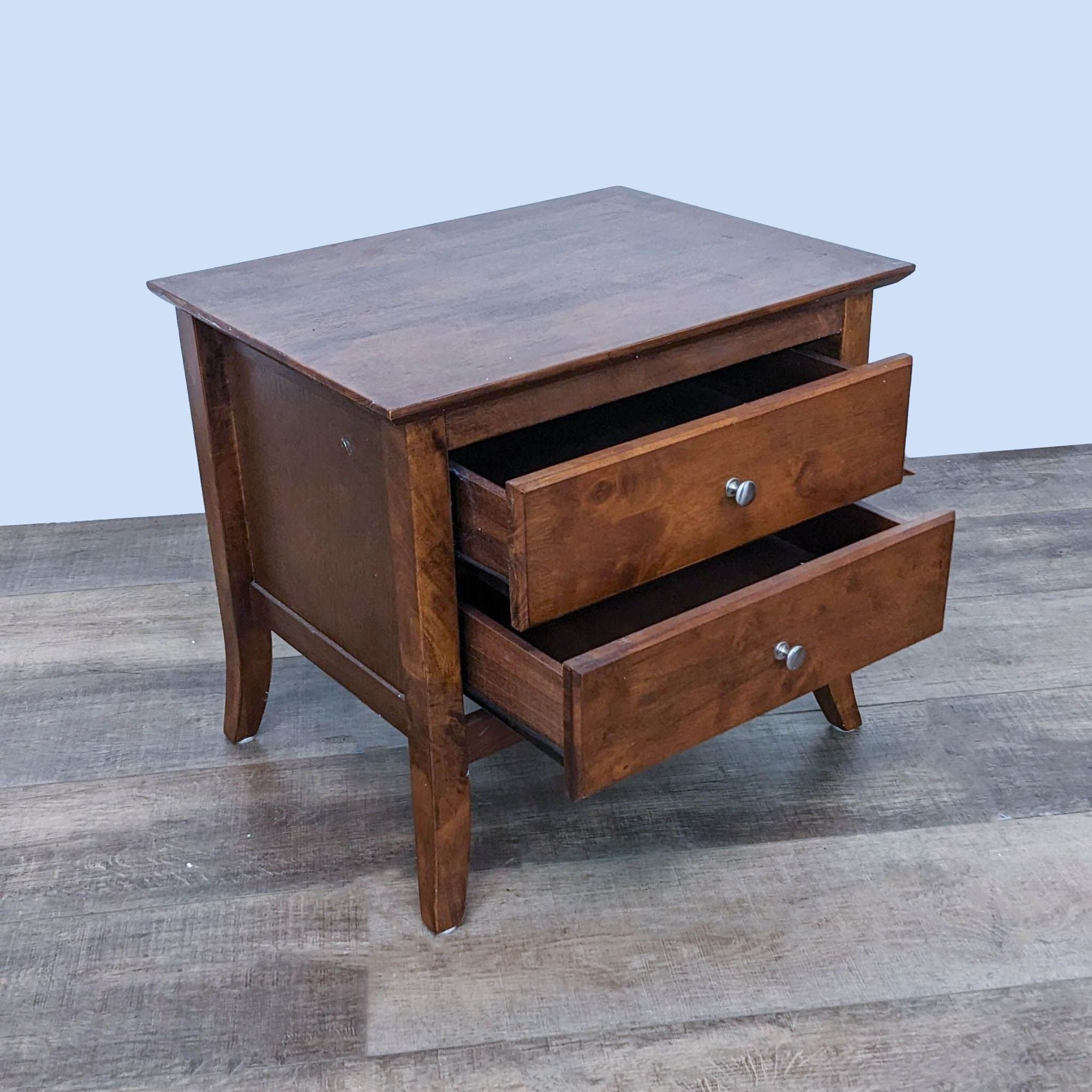 Opened drawers of Reperch end table, displaying interior, angled view on wooden floor.