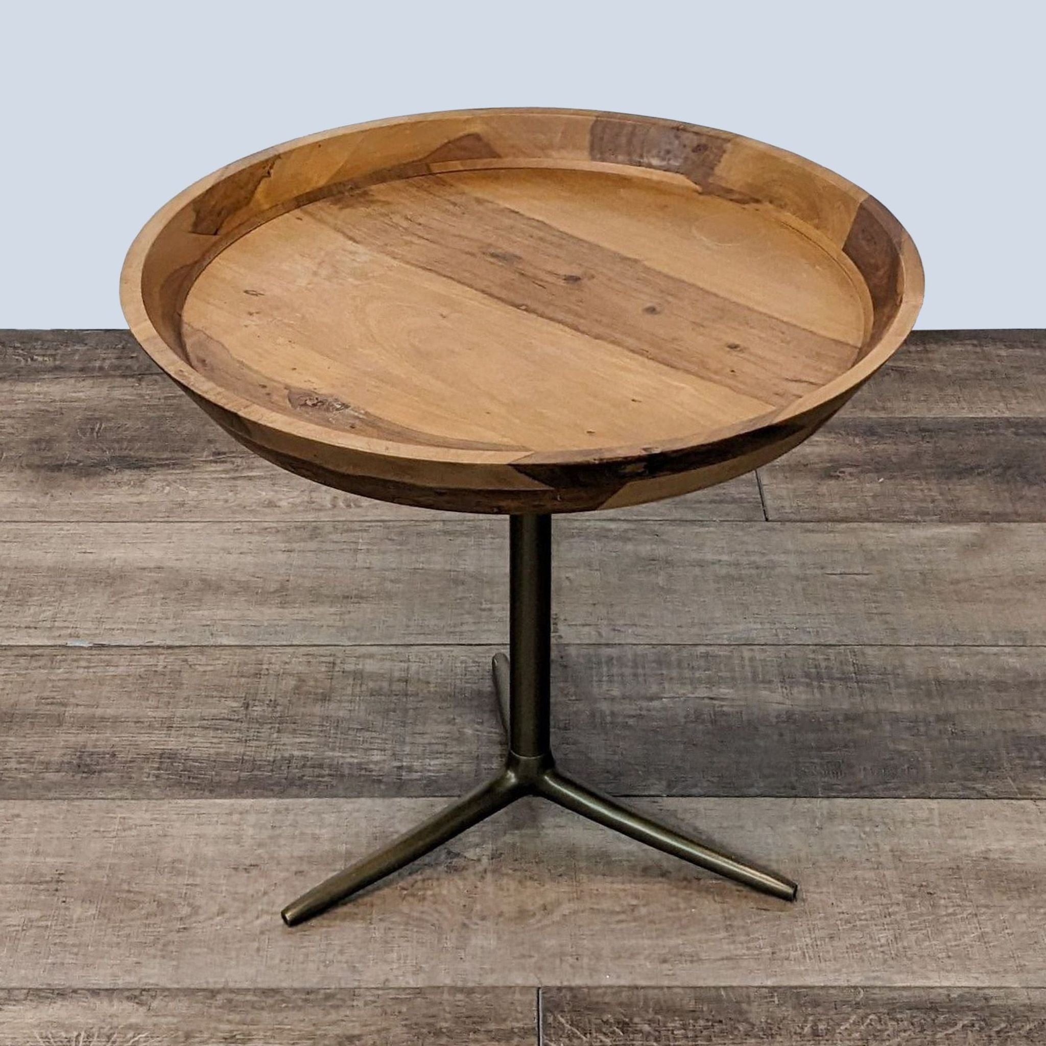 Round wooden tray top end table by West Elm, on a tripod metal base, set against a wooden floor.