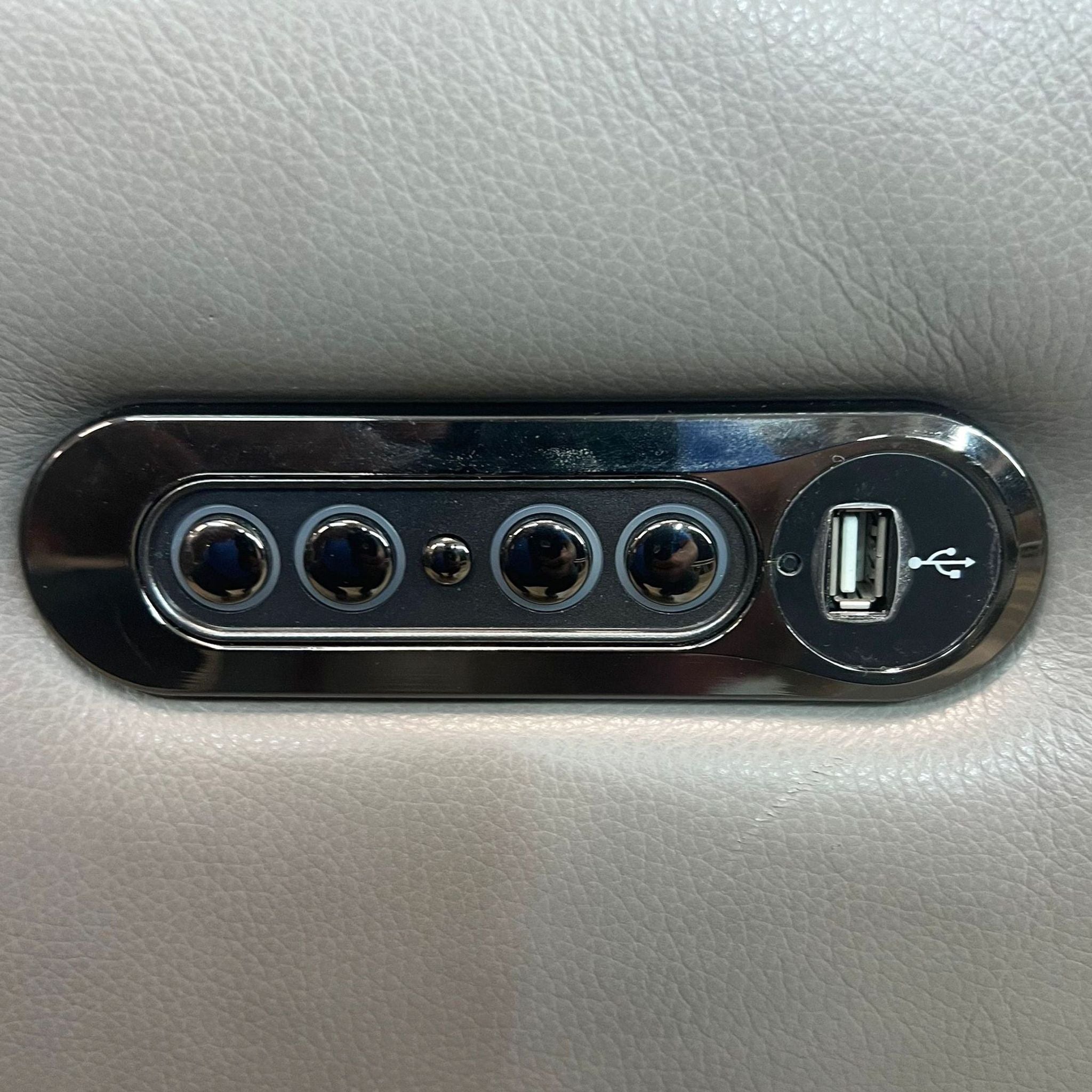 Close-up of a built-in USB port with controls on the Reperch grey leather loveseat.