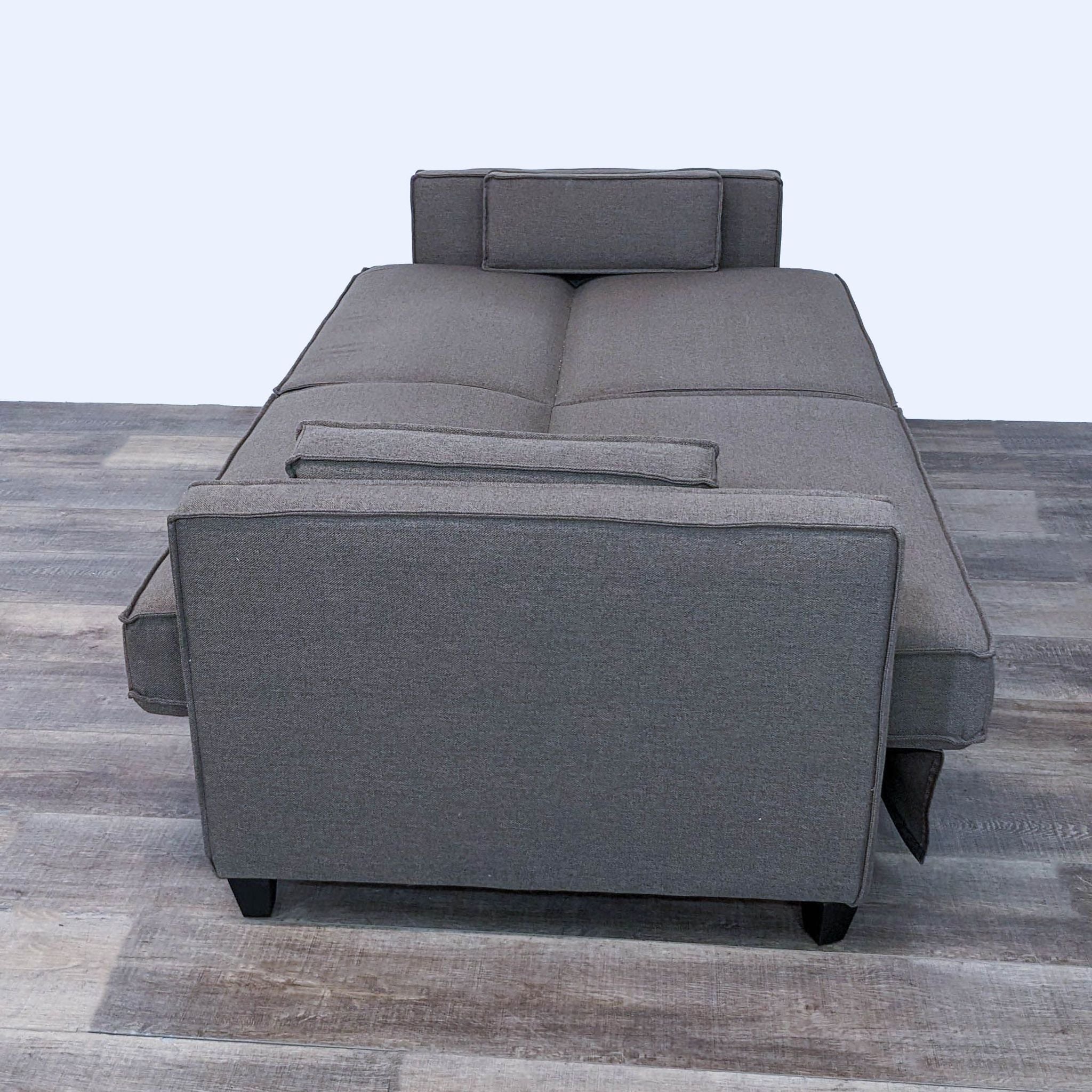 2. "Transitional loveseat from World Market expanded into a bed with grey fabric, showcasing its full-size sleeping surface."