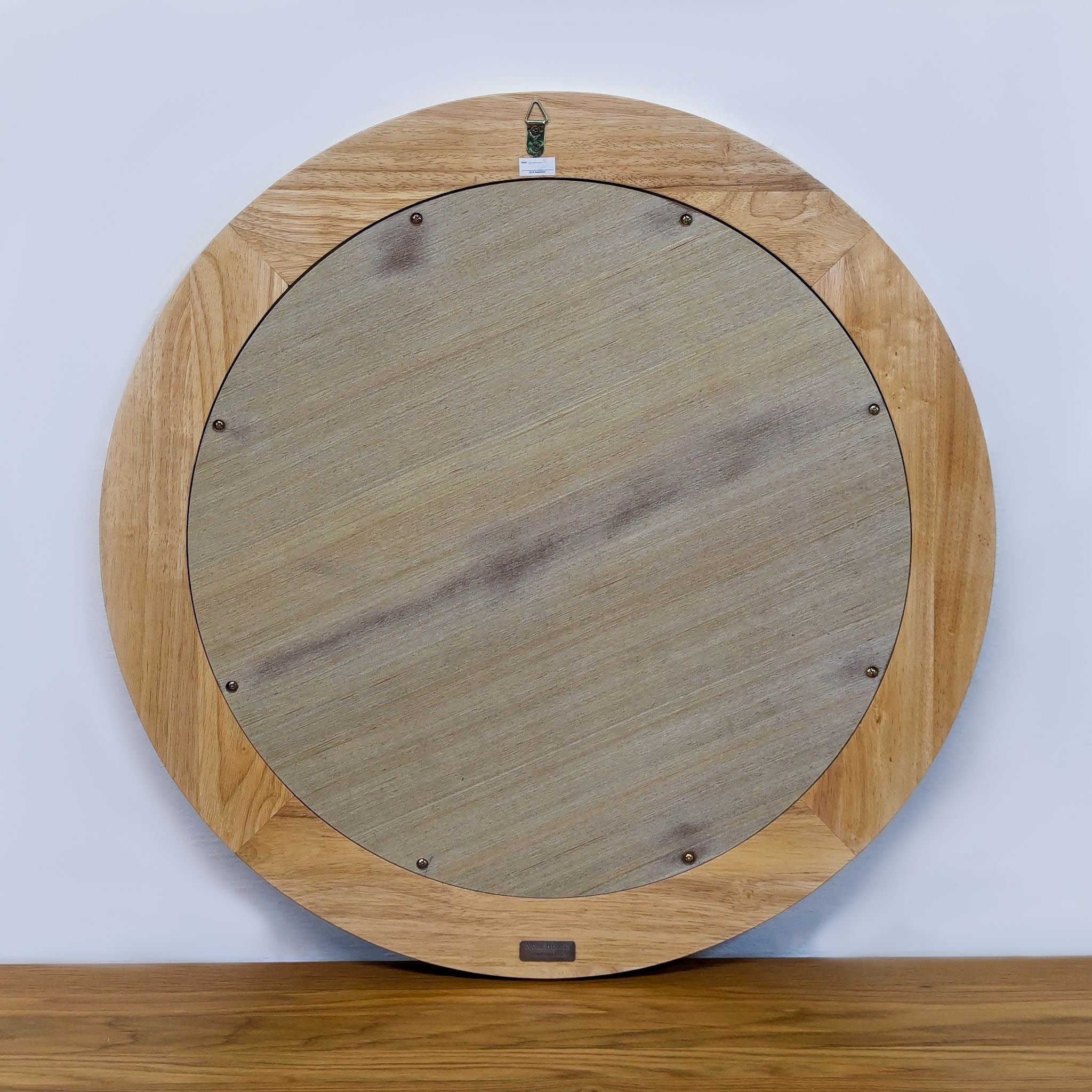 Back view of round mirror with wood backing and hanger.