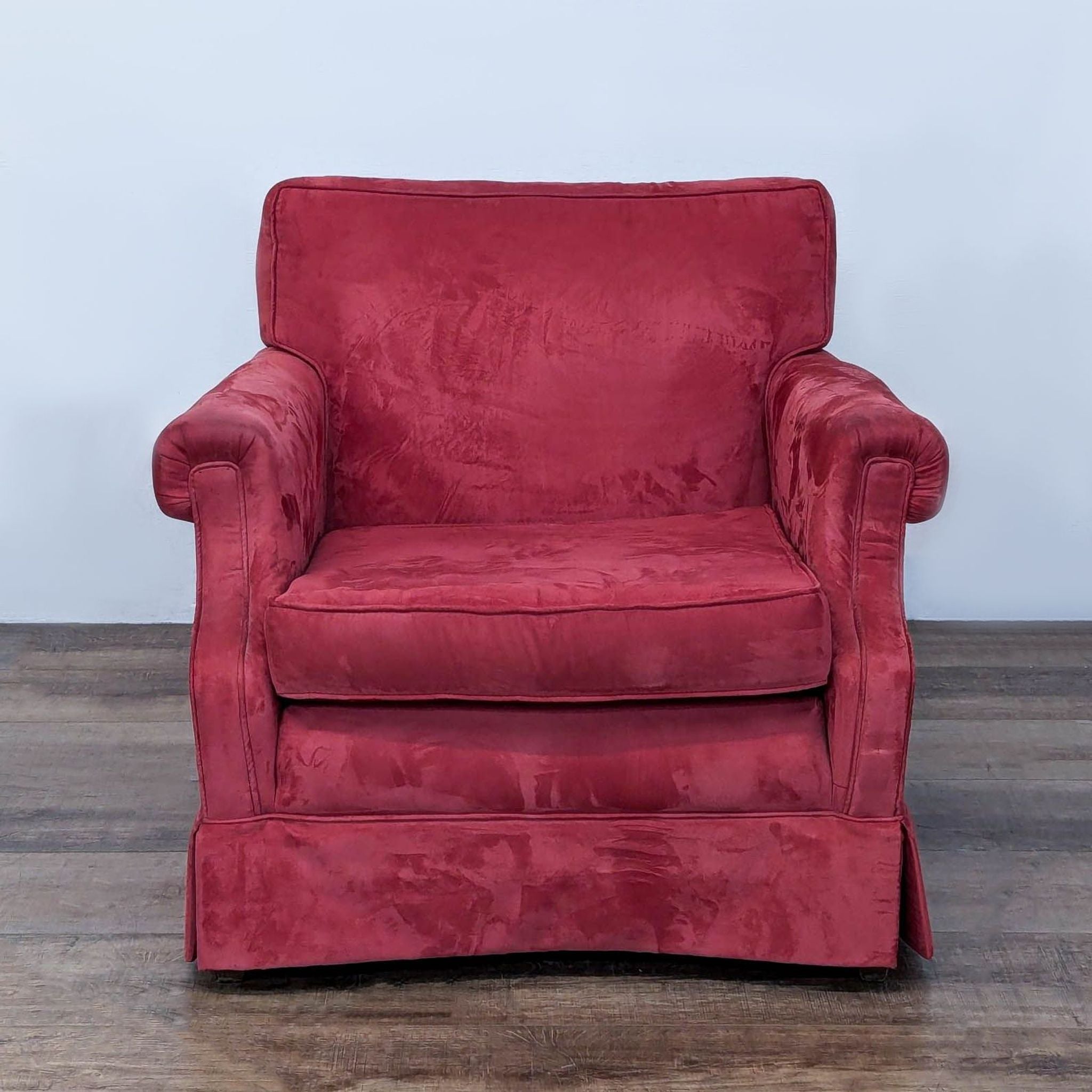Red armchair with plush fabric and rolled arms on a wooden floor by Ethan Allen.