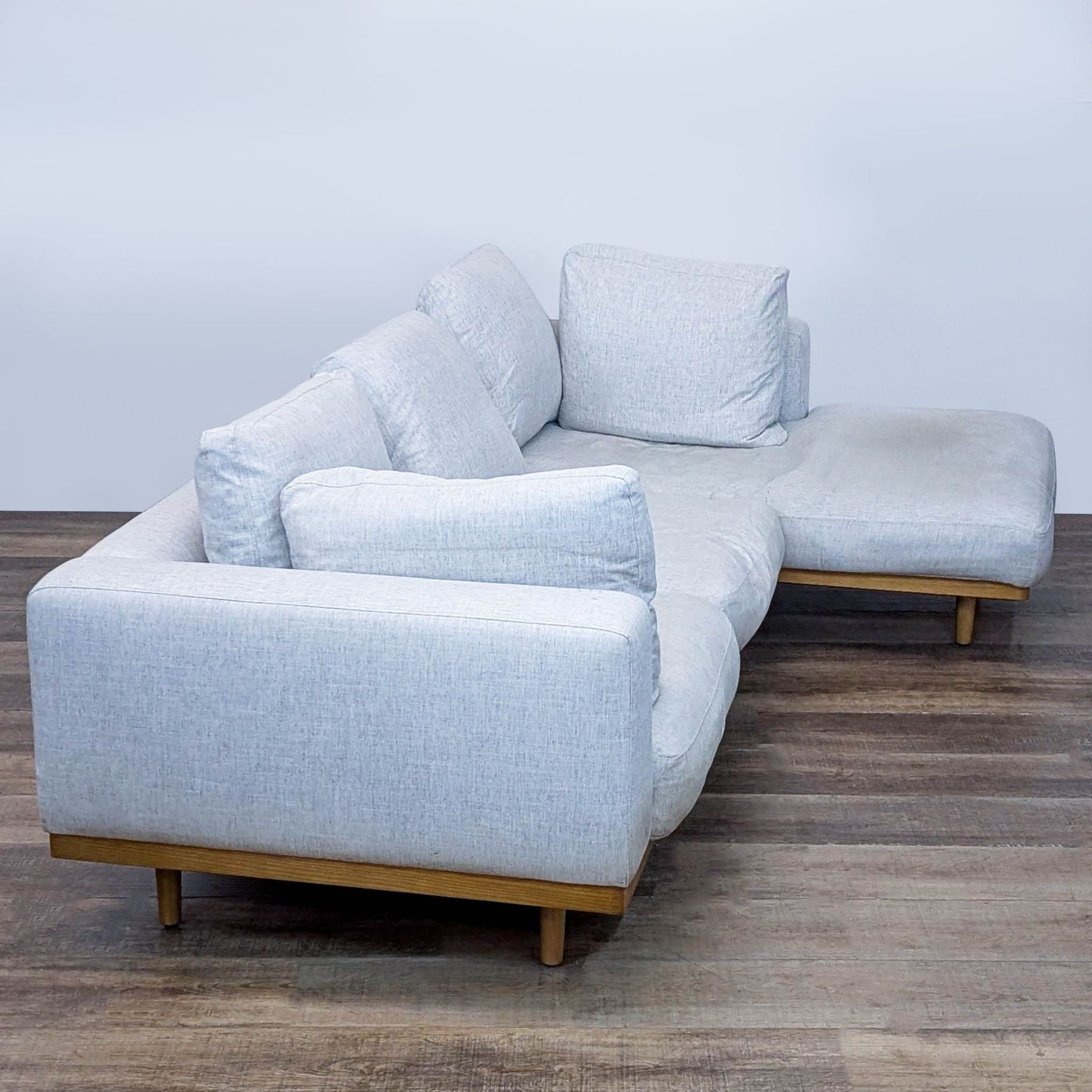 Side view of a light gray sectional on a wood floor.