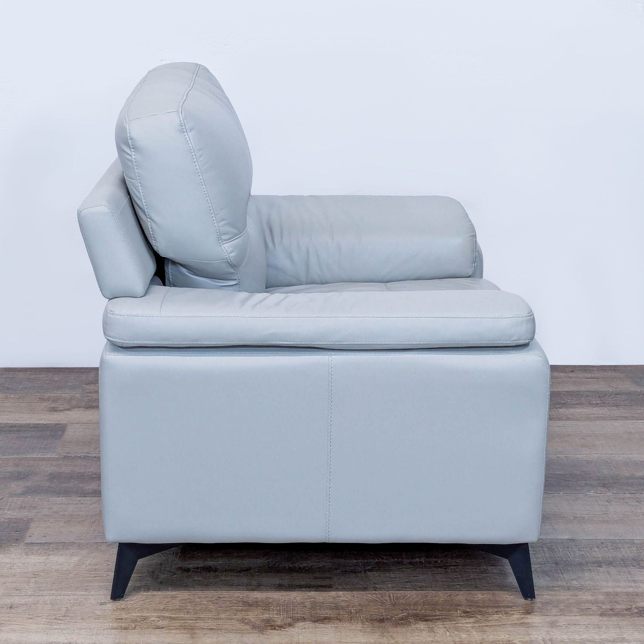 Reperch Lounge armchair side profile in light grey, highlighting its modern, cushioned style.