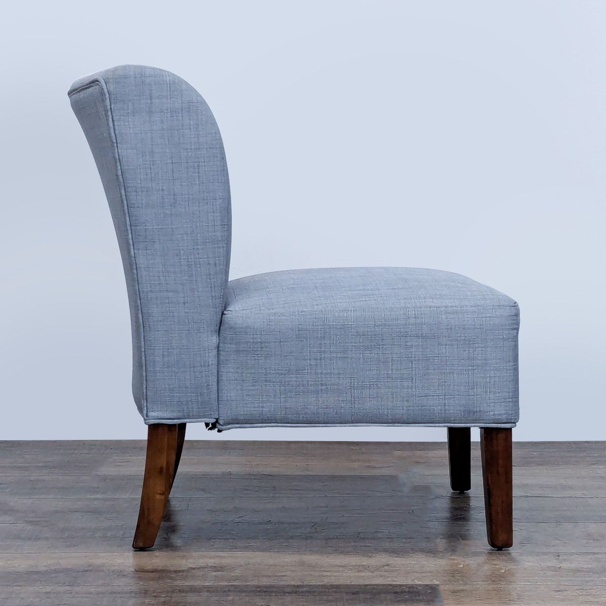 Profile view of Reperch lounge chair featuring a curved backrest and elegant wooden legs.