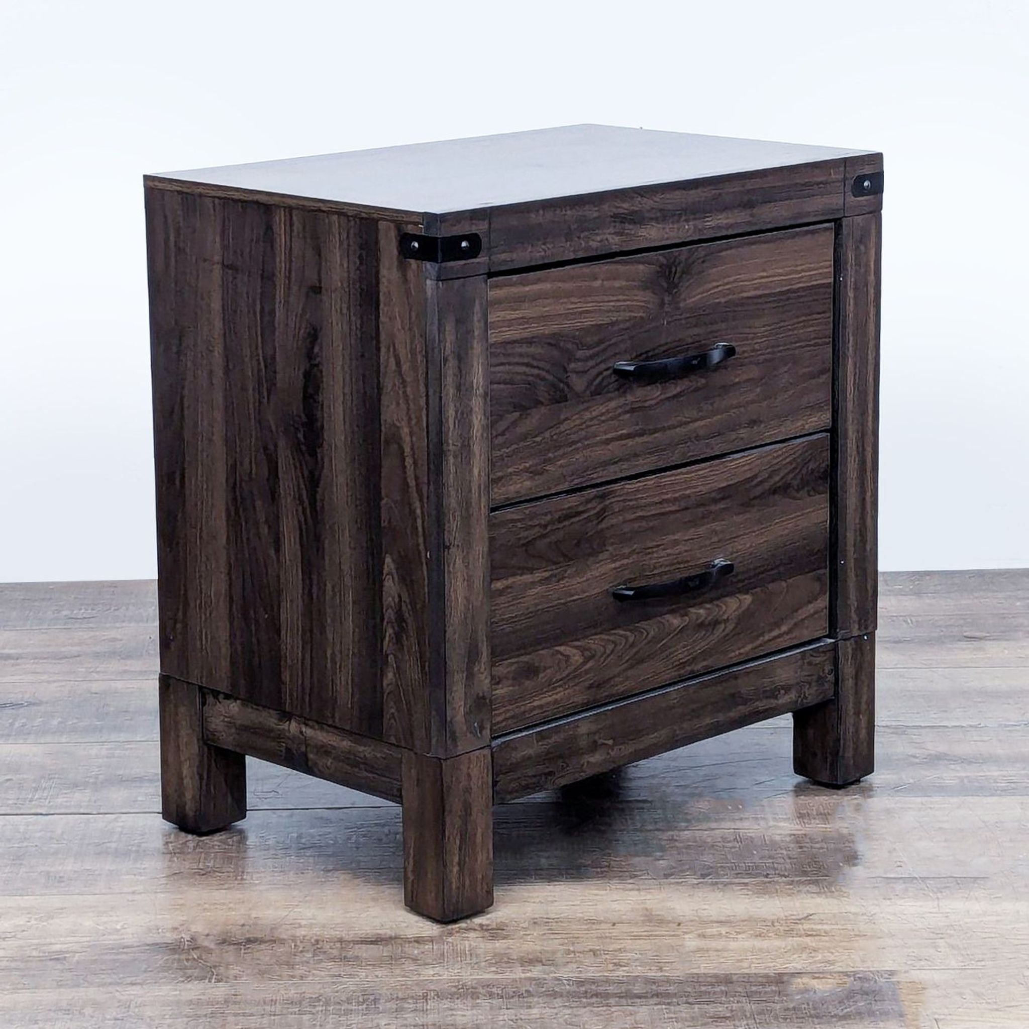 Side view of a dark wooden Living Spaces end table with closed drawers.